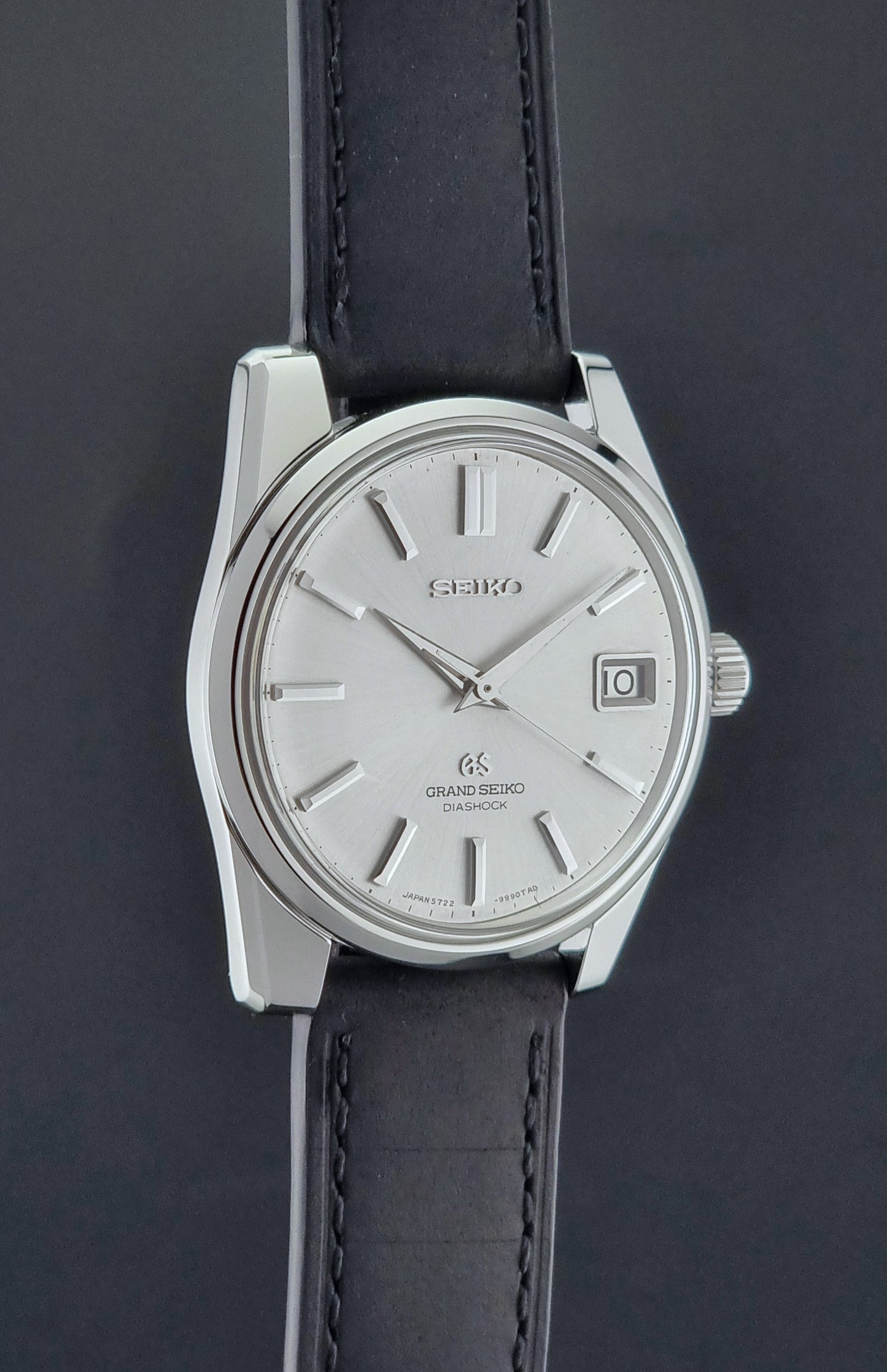 Vintage Grand Seiko Wristwatch 5722-9991 with black leather strap on a gray background side profile