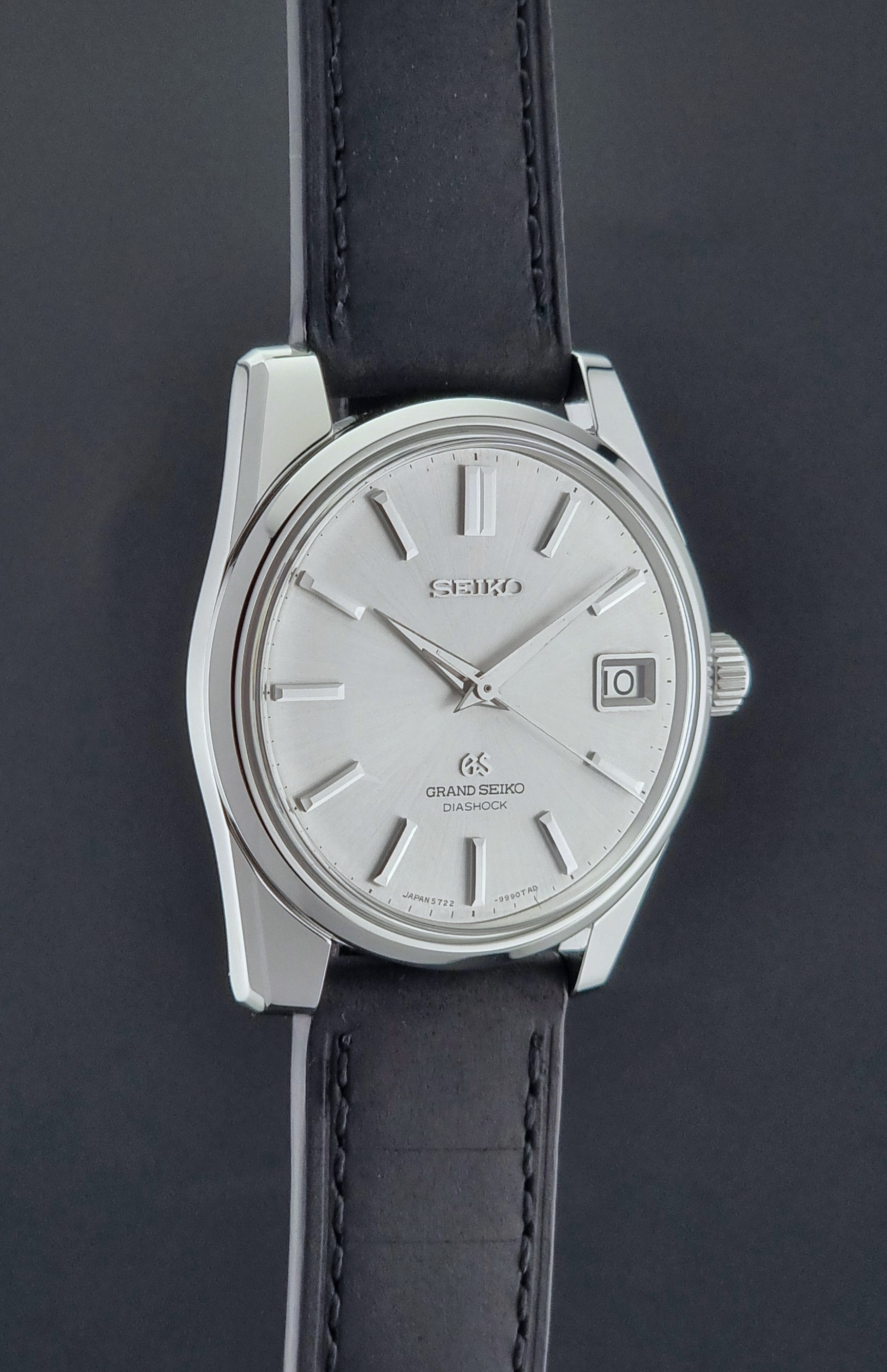 Vintage Grand Seiko Wristwatch 5722-9991 with black leather strap on a gray background side profile