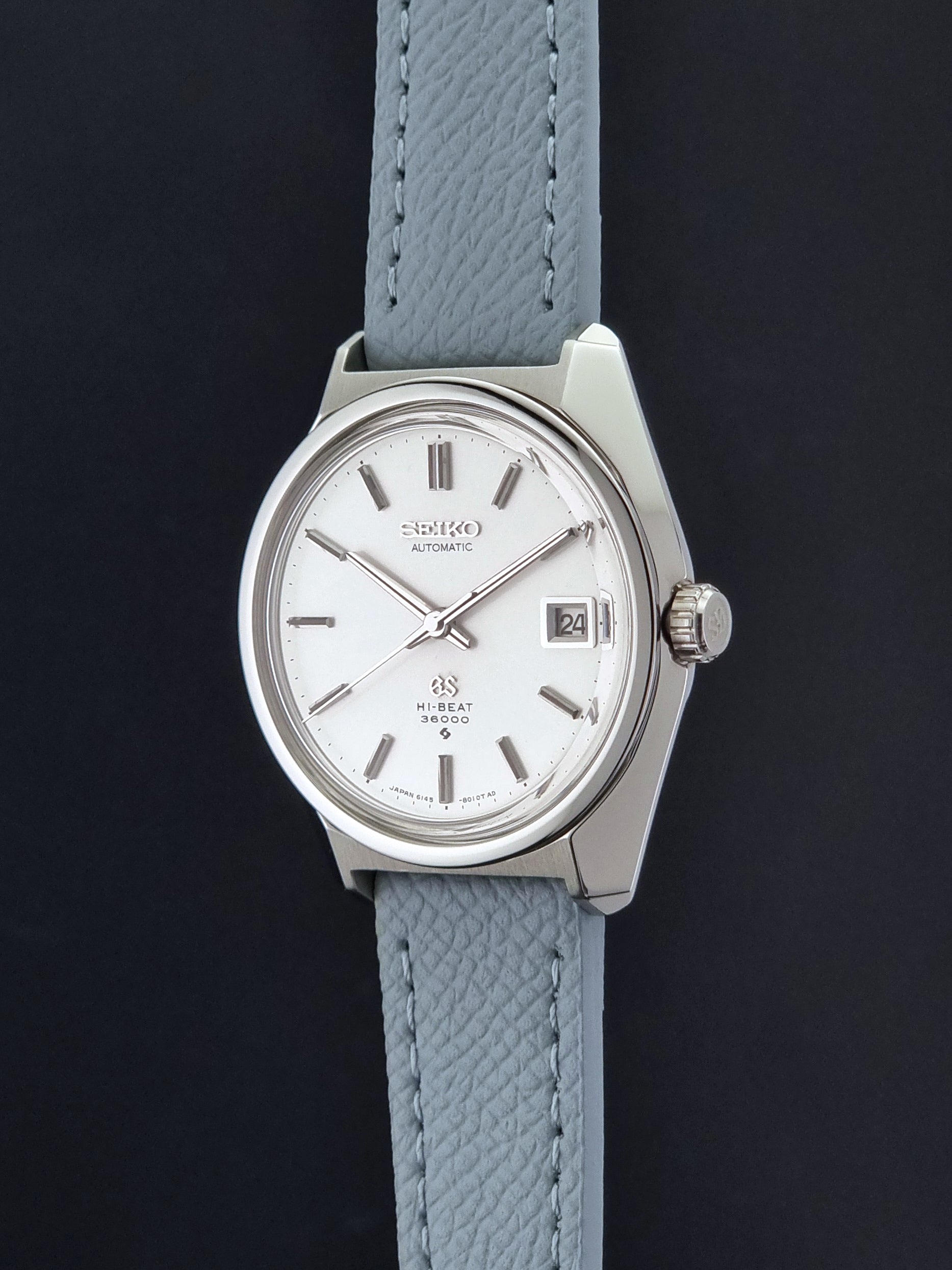 Vintage Grand Seiko 6145-8000 on a grey leather strap on a dark background crown profile view