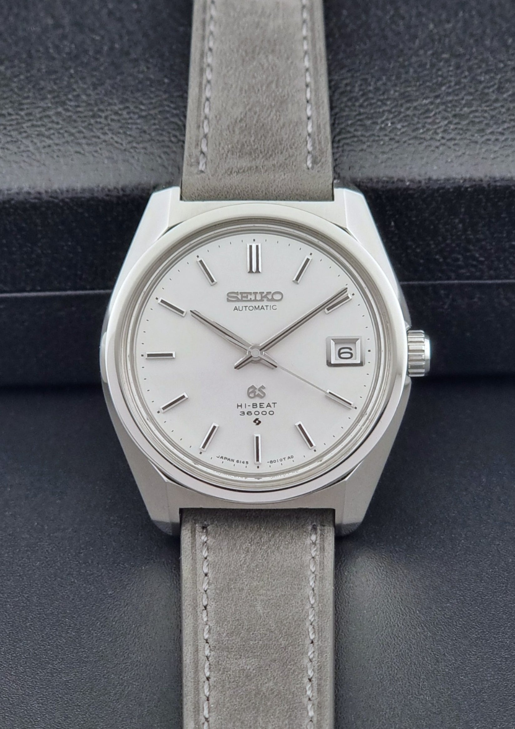 Grand Seiko 6145-8000 watch with gray leather strap on a dark background