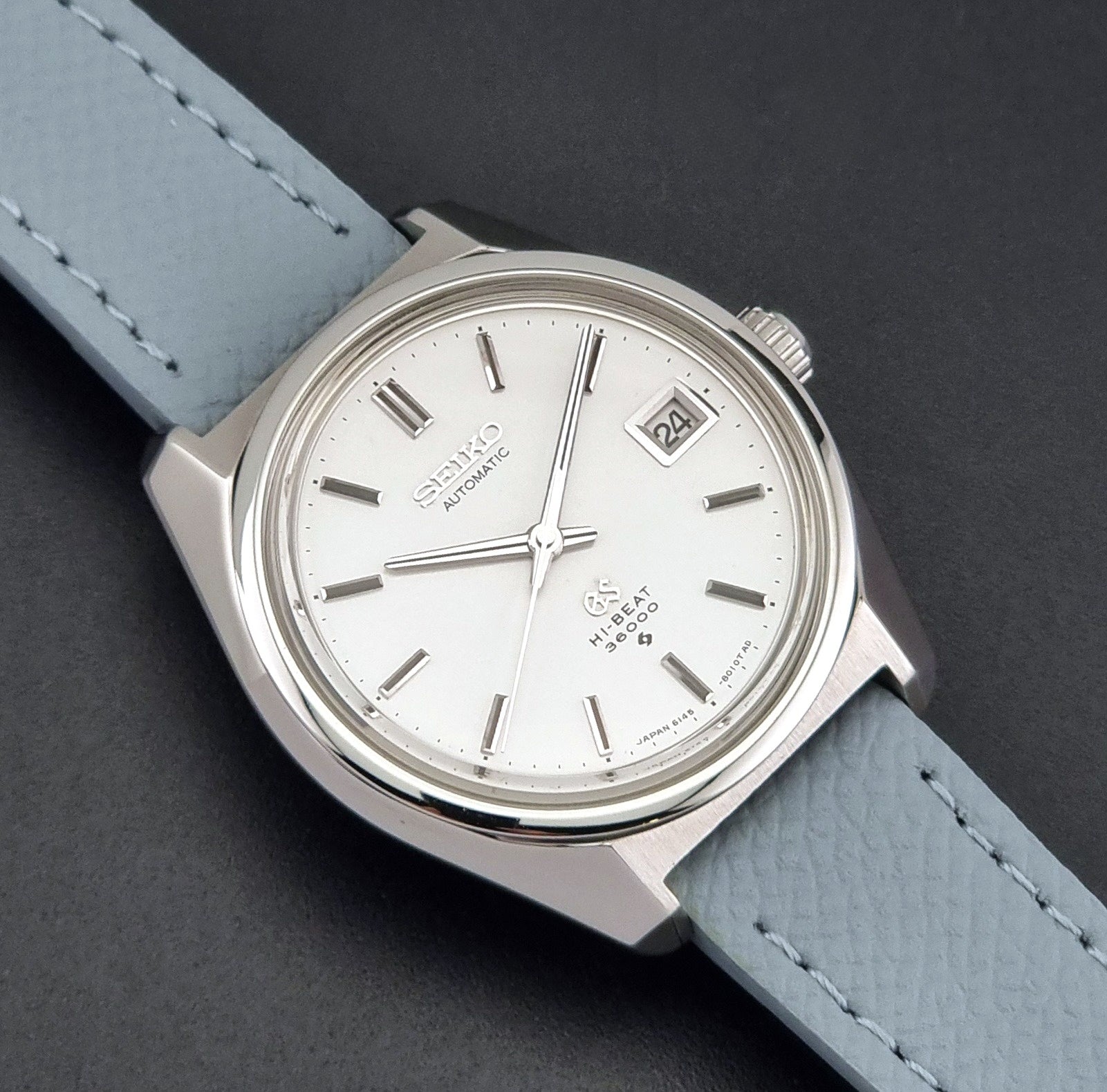 Vintage Grand Seiko 6145-8000 on a grey leather strap on a dark background close up dial view