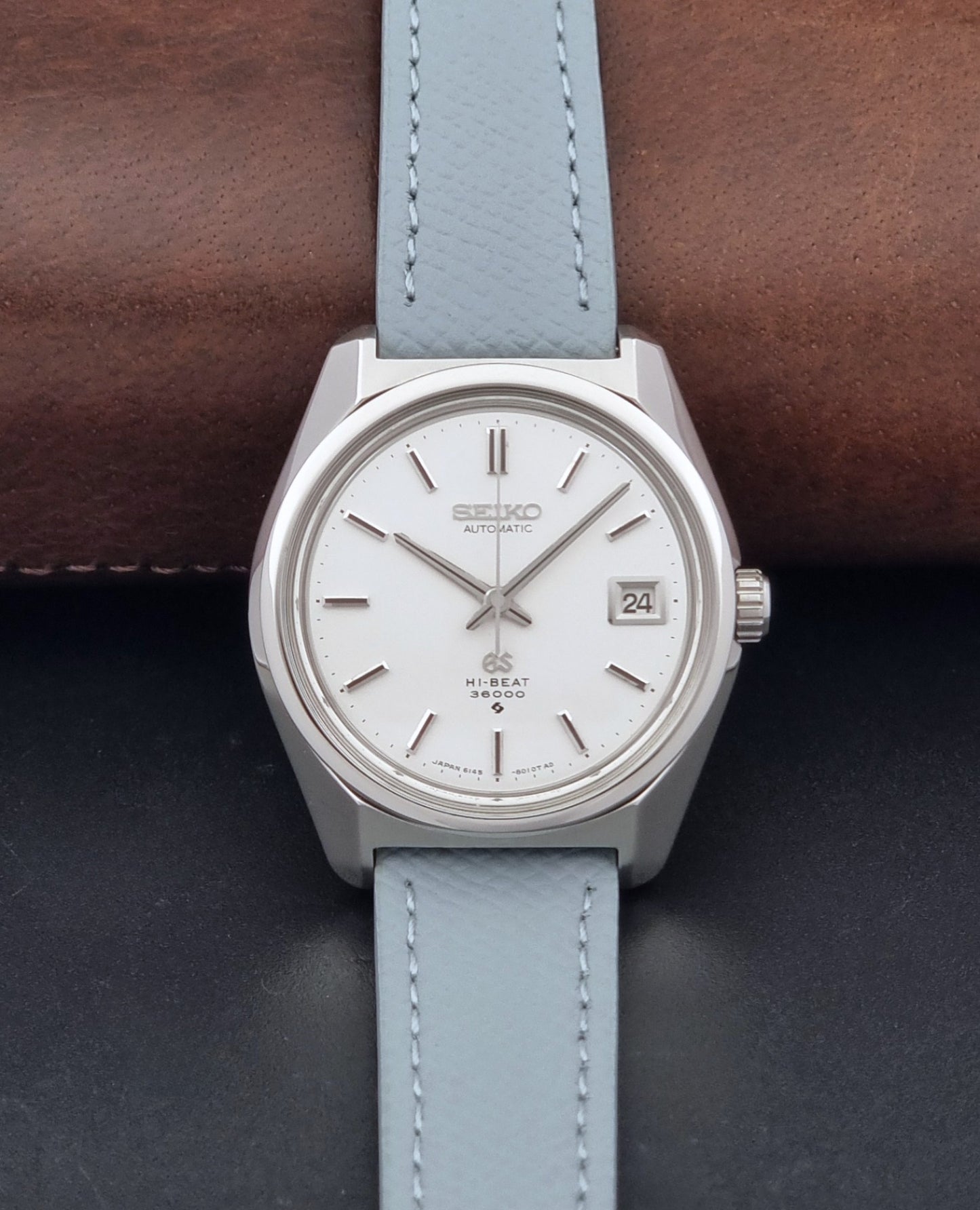 Vintage Grand Seiko 6145-8000 on a grey leather strap on a dark background dial view
