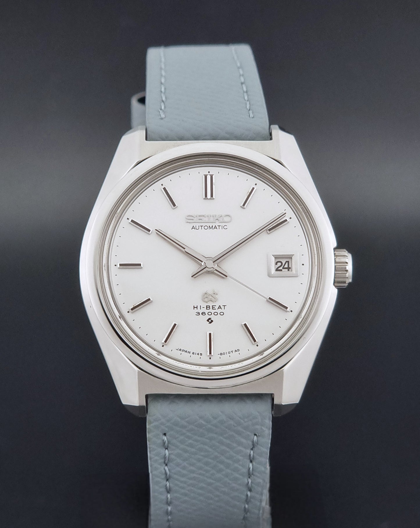 Vintage Grand Seiko 6145-8000 on a grey leather strap on a dark background close dial view