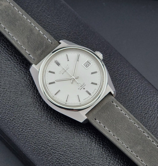 Grand Seiko 6145-8000 Watch with gray strap and silver case on a dark textured surface