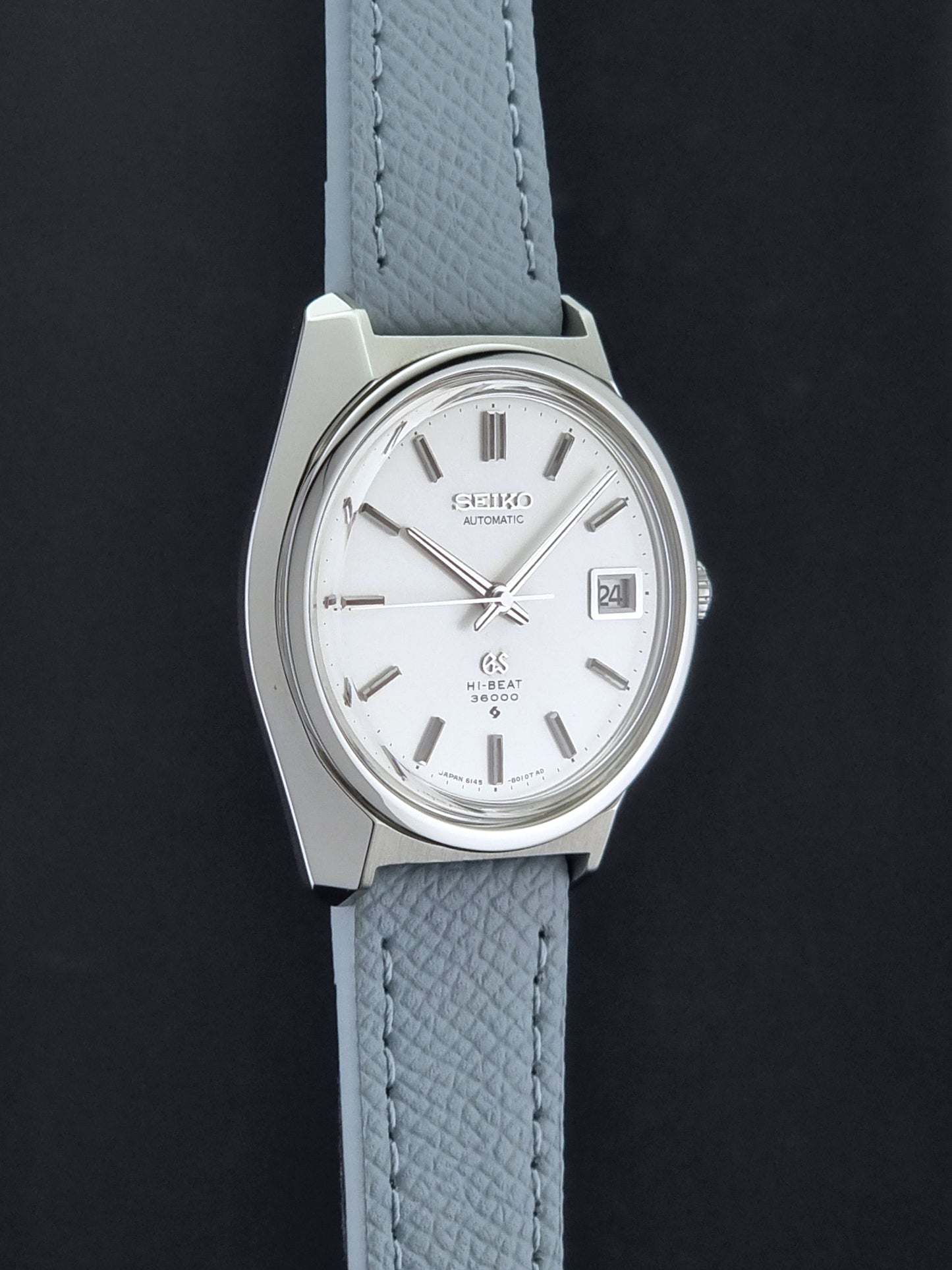 Vintage Grand Seiko 6145-8000 on a grey leather strap on a dark background side profile view
