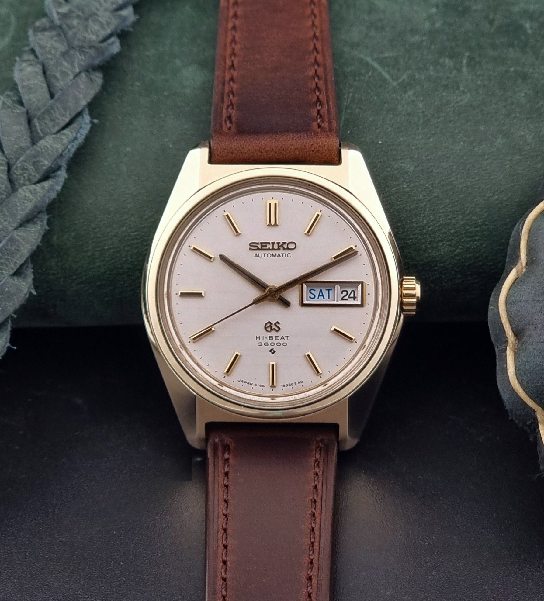 Vintage  Grand Seiko watch 6146-8000 watch with gold case and brown leather strap on a dark background dial view