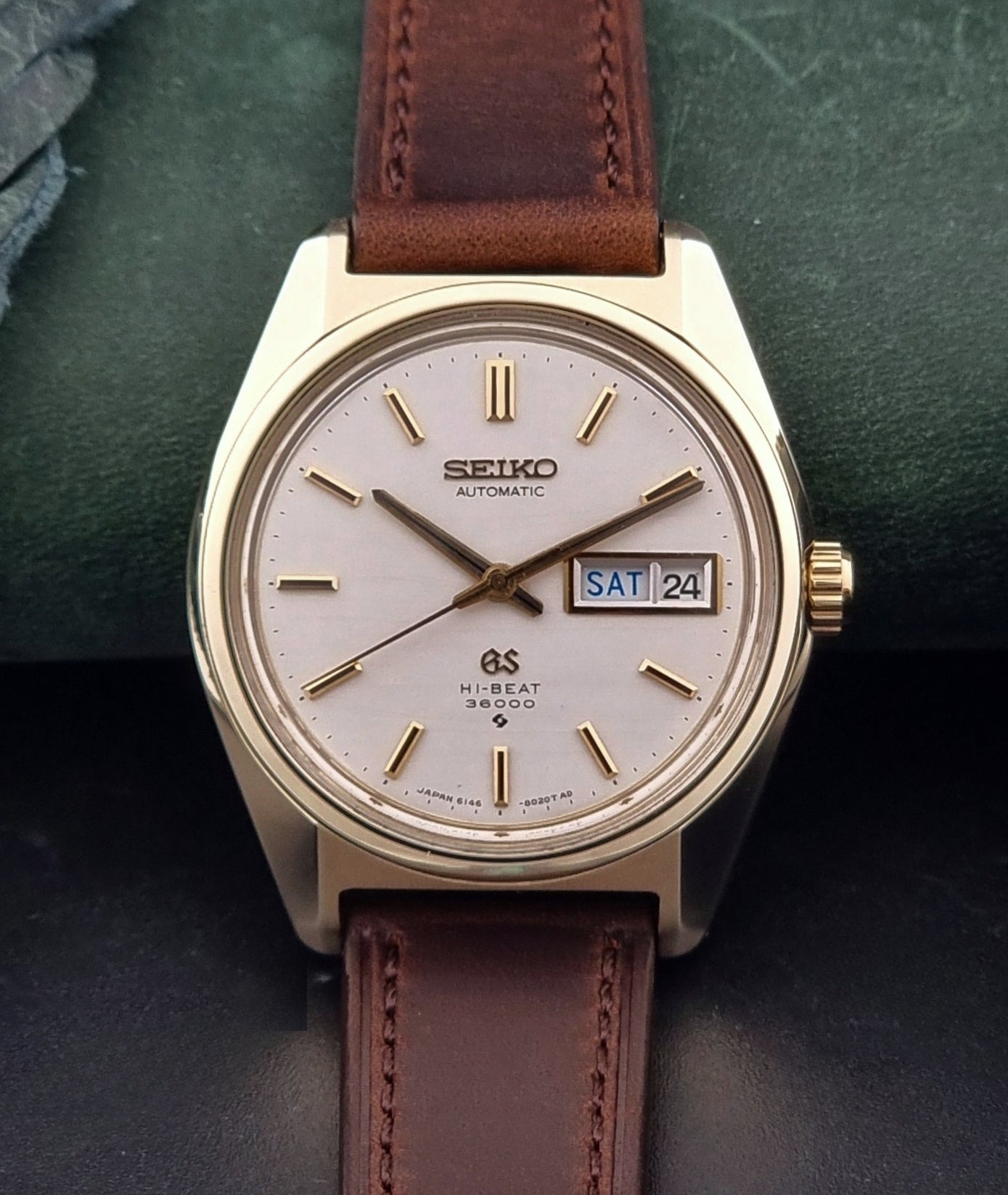 Vintage  Grand Seiko watch 6146-8000 watch with gold case and brown leather strap on a dark background front
