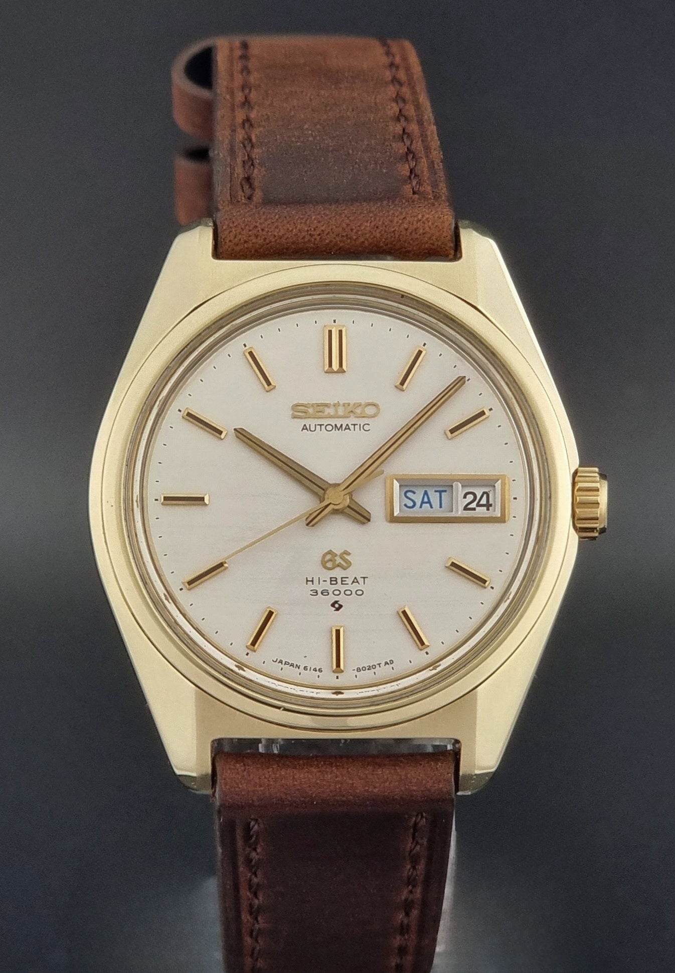 Vintage  Grand Seiko watch 6146-8000 watch with gold case and brown leather strap on a dark background close dial view