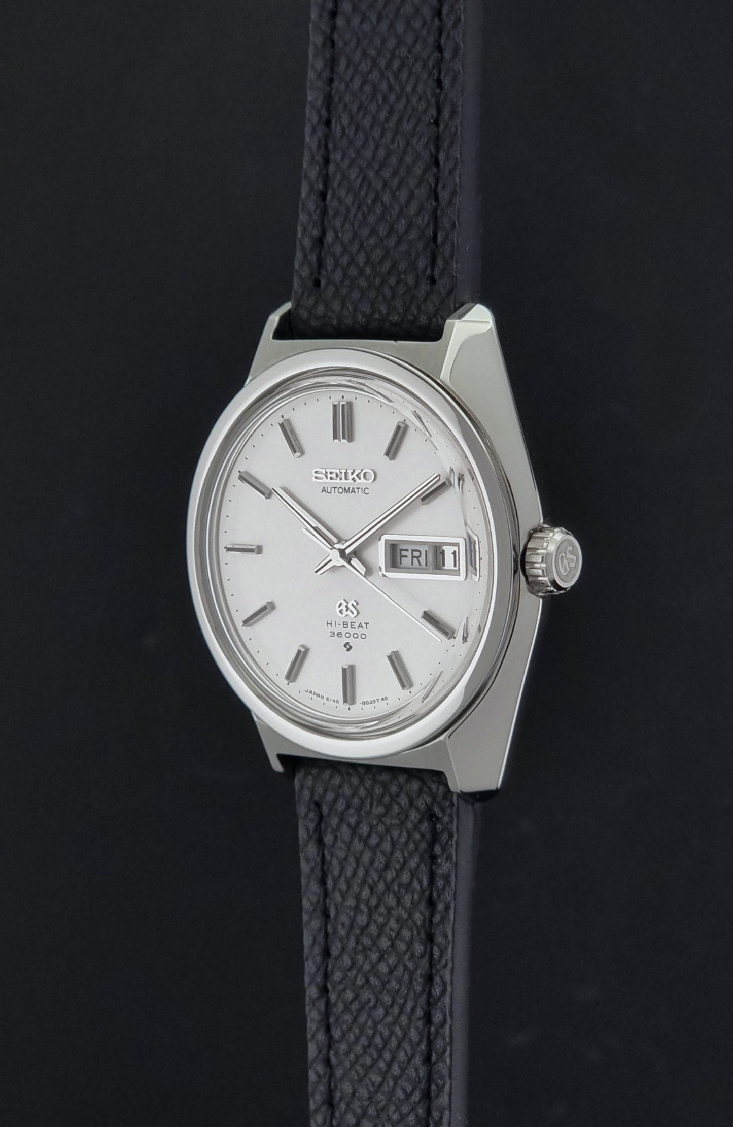 Vintage Grand Seiko 6146-8000 Wristwatch with a black leather strap on a dark background crown profile view