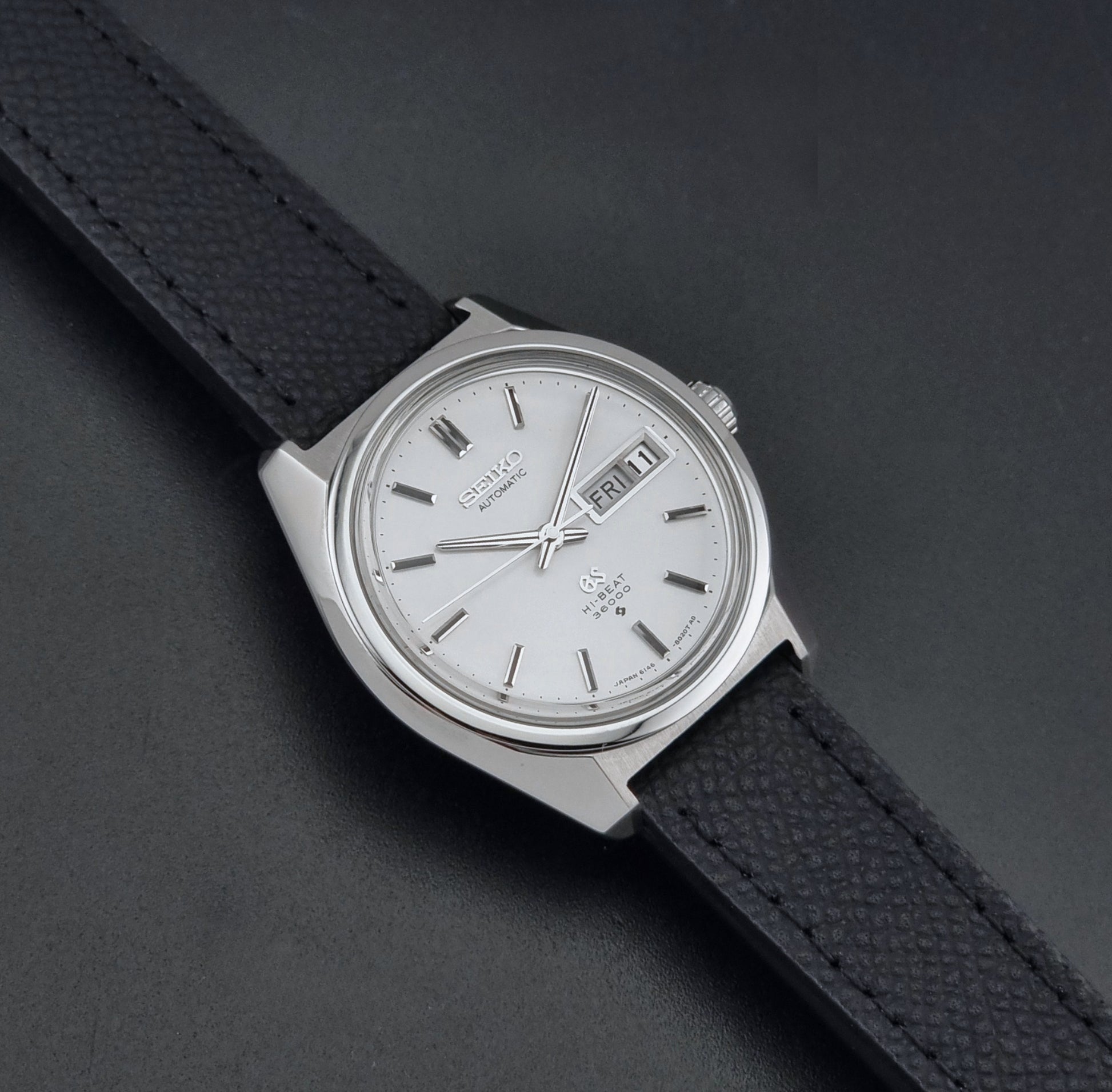 Vintage Grand Seiko 6146-8000 Wristwatch with a black leather strap on a dark background dial