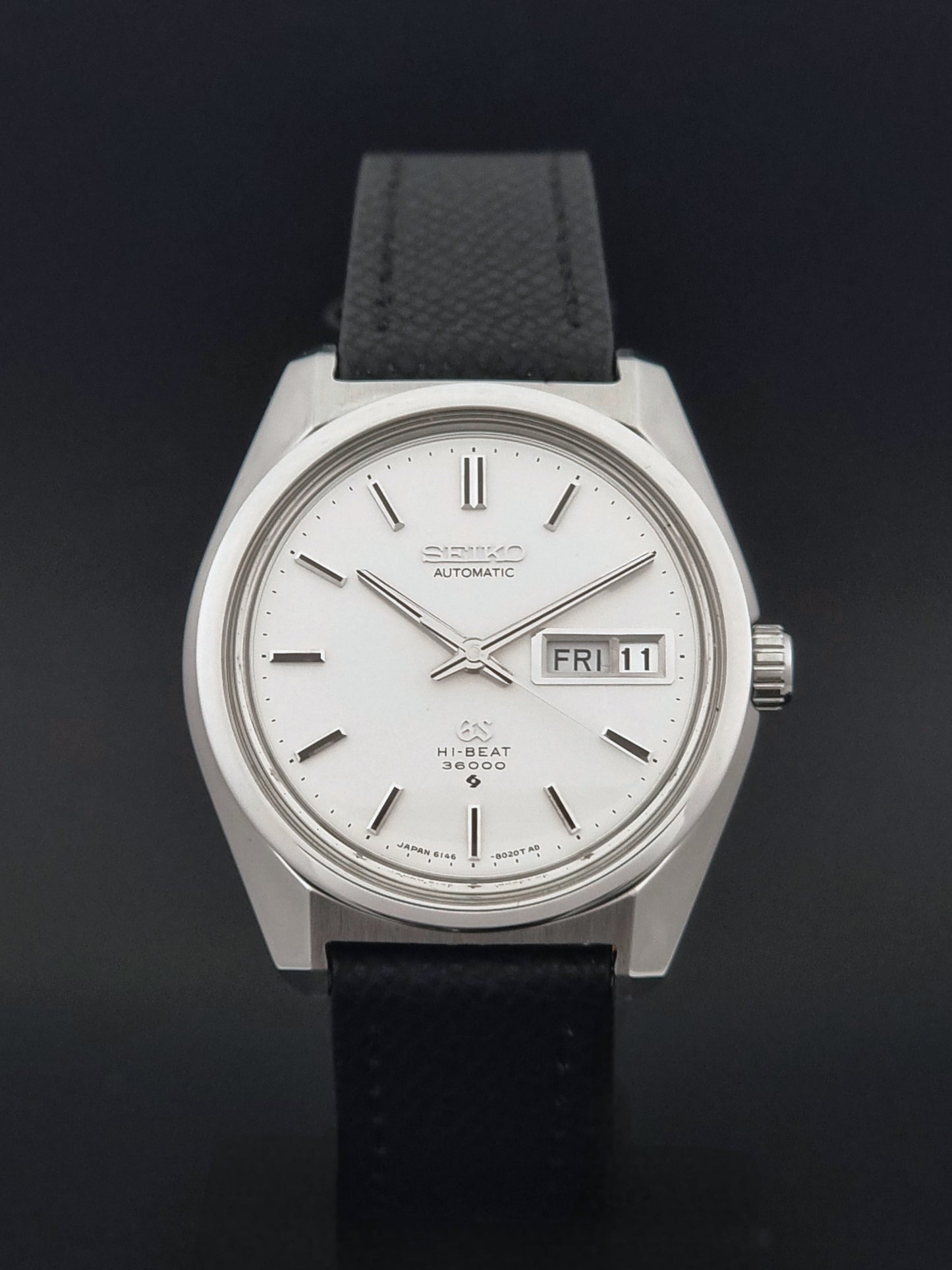 Vintage Grand Seiko 6146-8000 Wristwatch with a black leather strap on a dark background close dial view