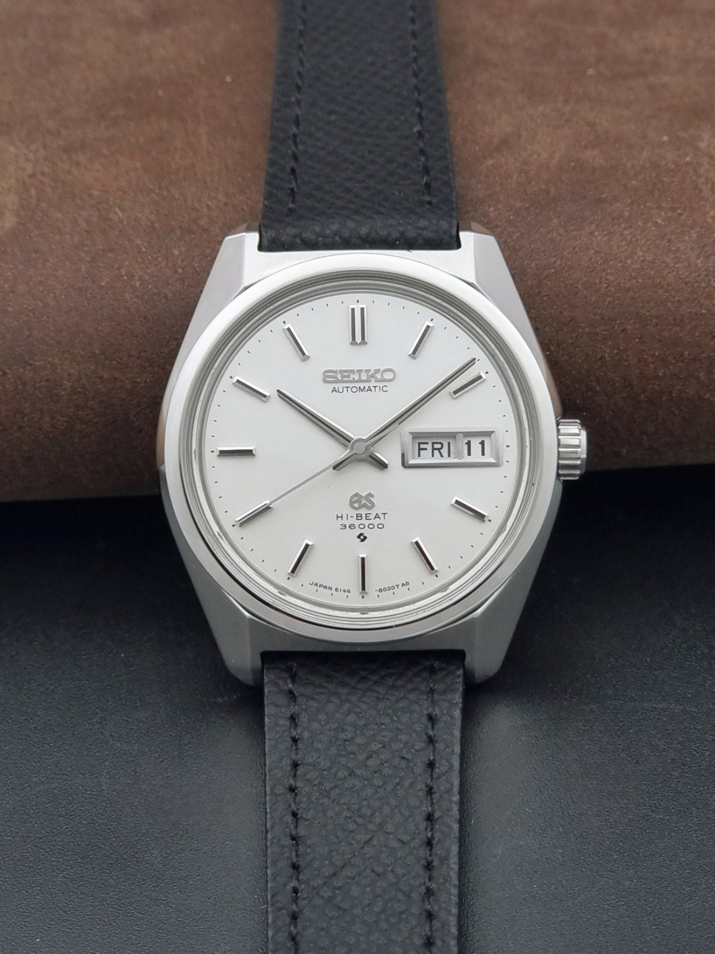 Vintage Grand Seiko 6146-8000 Wristwatch with a black leather strap on a dark background dial view