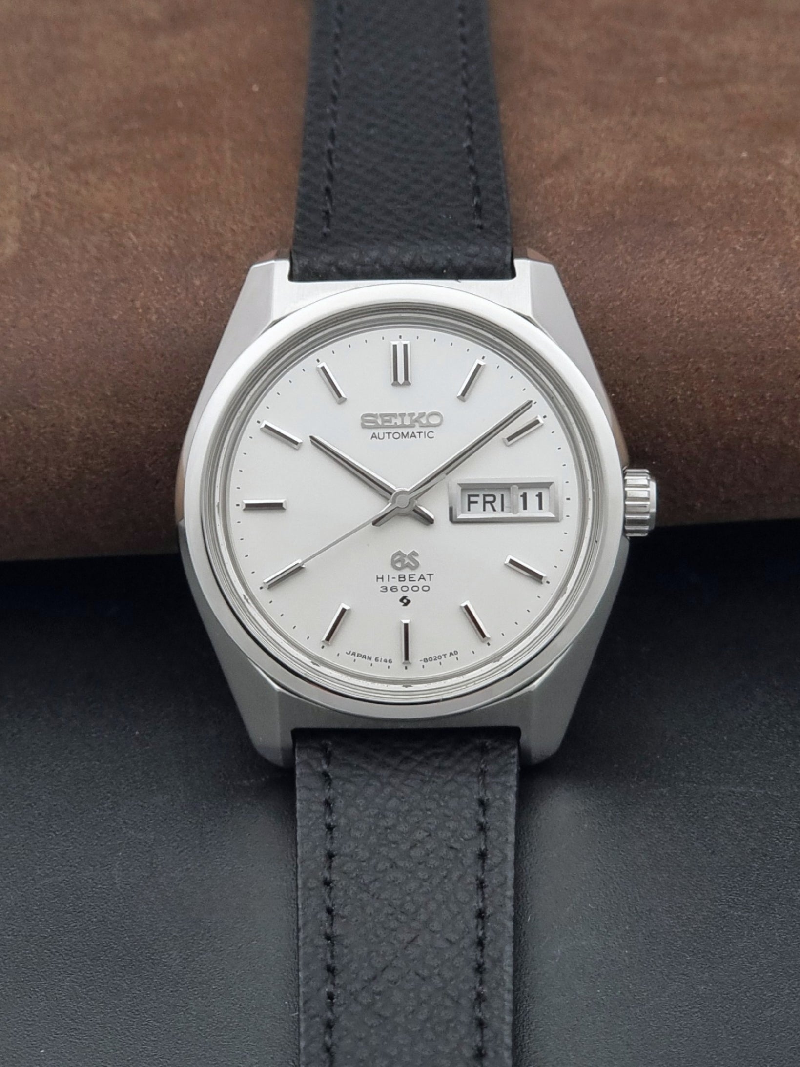 Vintage Grand Seiko 6146-8000 Wristwatch with a black leather strap on a dark background dial view