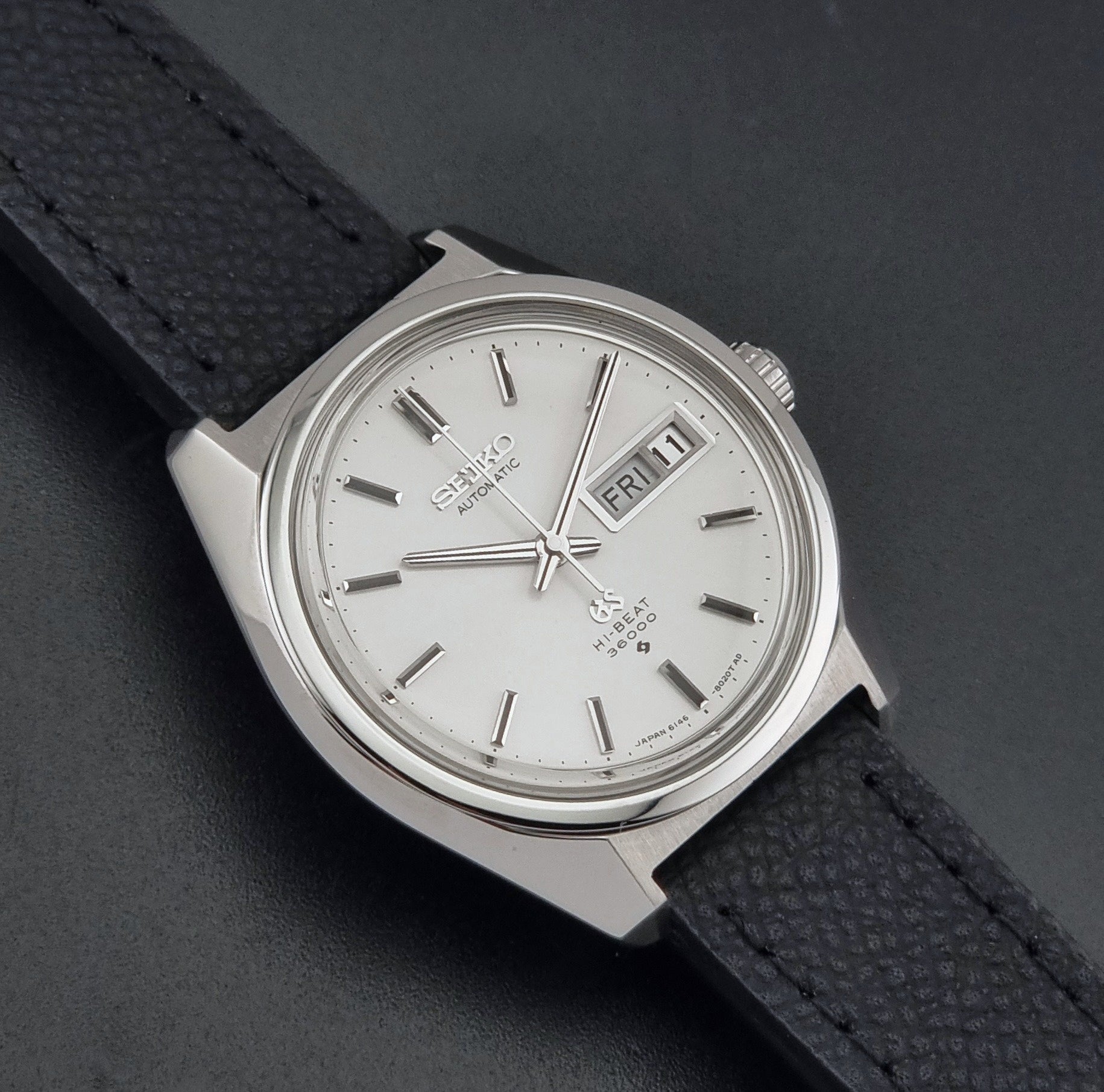 Vintage Grand Seiko 6146-8000 Wristwatch with a black leather strap on a dark background close up dial view