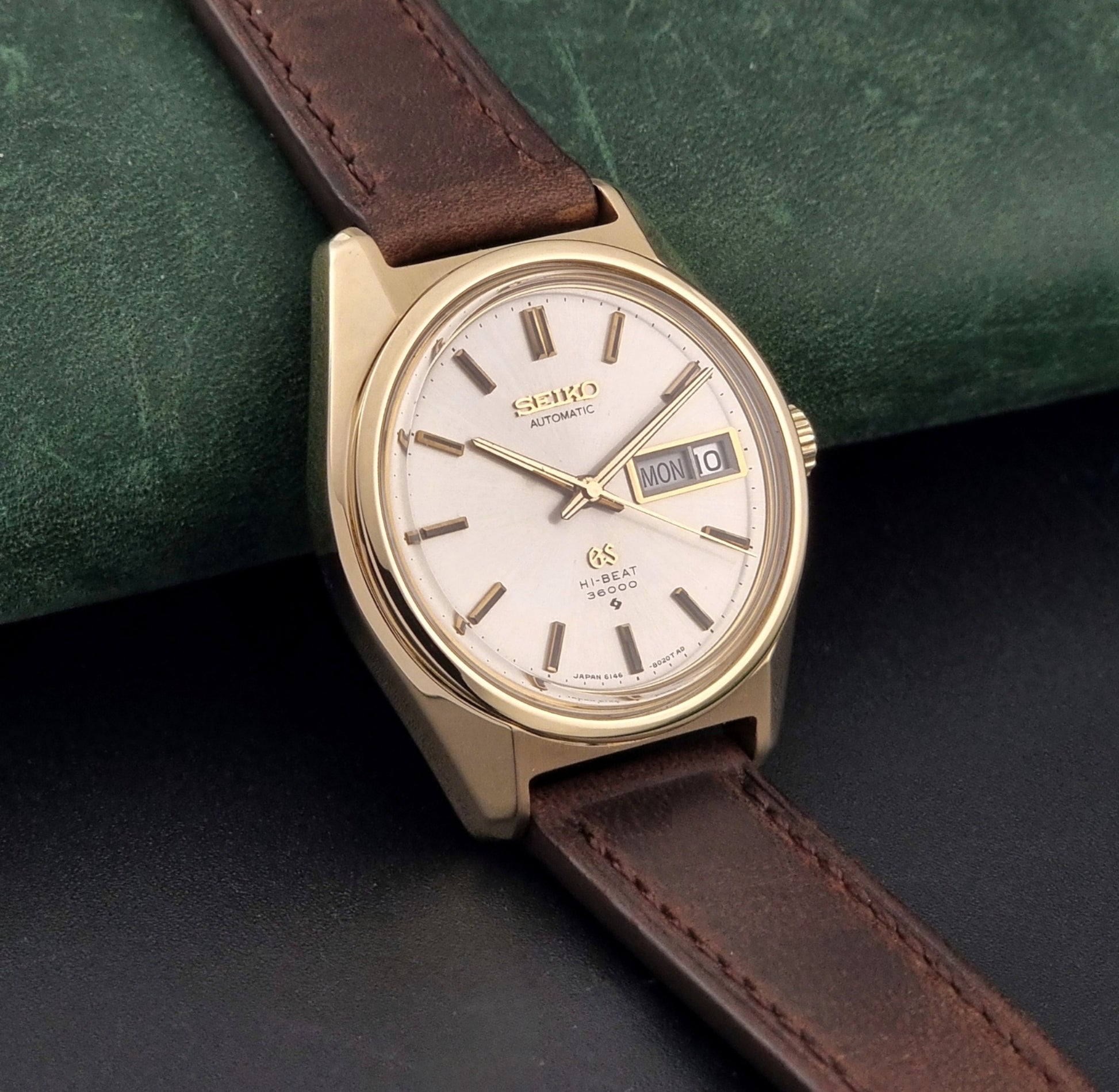 Vintage Grand Seiko watch 6146-8000 in gold with a brown leather strap side view