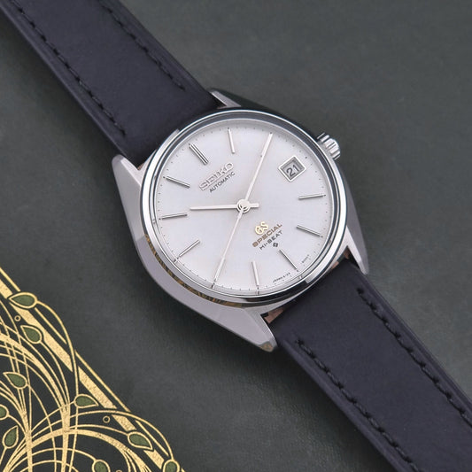 Vintage Grand Seiko Wristwatch with a white dial and black strap on a dark background