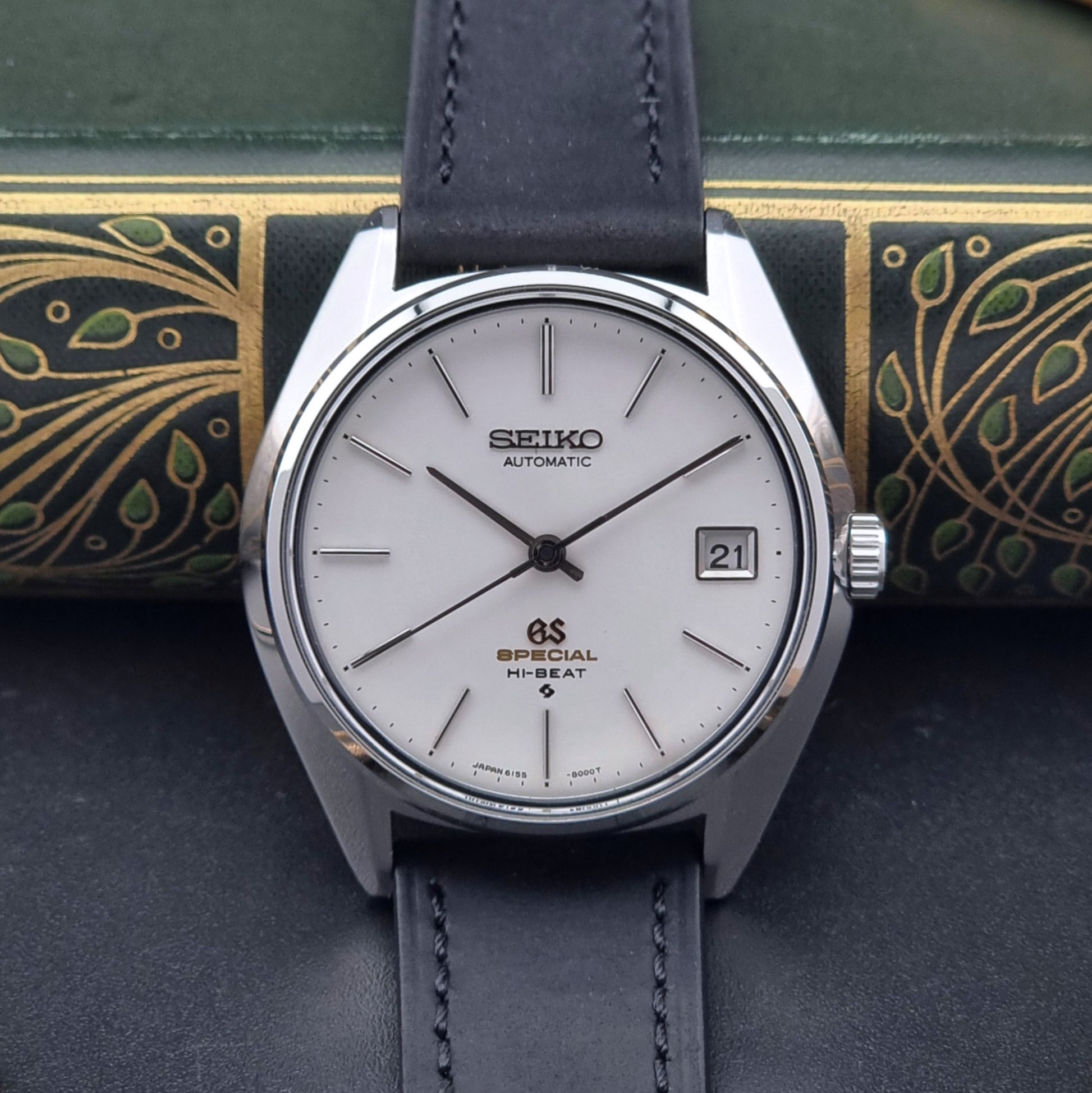 Vintage Grand Seiko watch watch with black leather strap on a decorative background