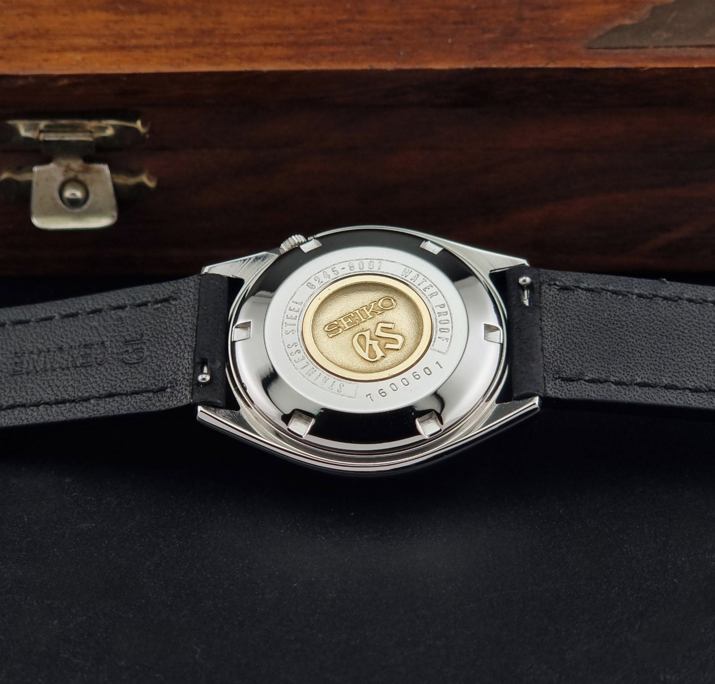 Vintage Grand Seiko 6245-9001 Wristwatch with a black leather strap on a dark background case back view