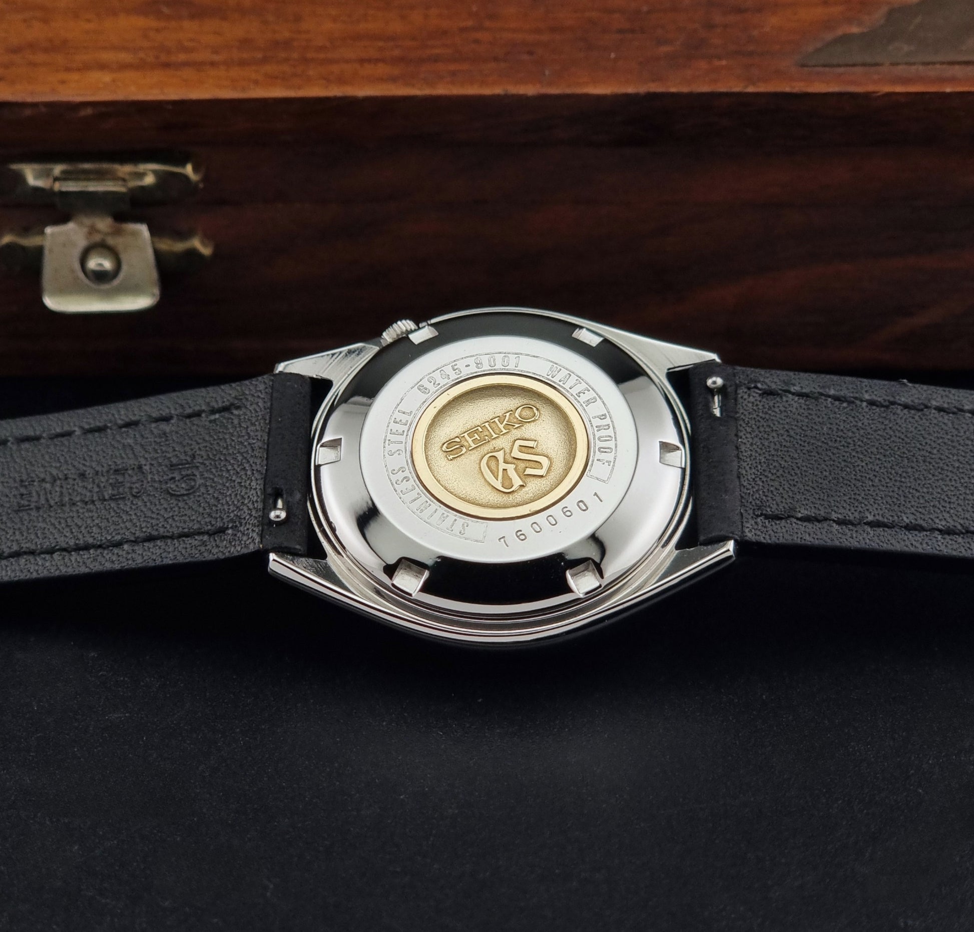 Vintage Grand Seiko 6245-9001 Wristwatch with a black leather strap on a dark background case back view