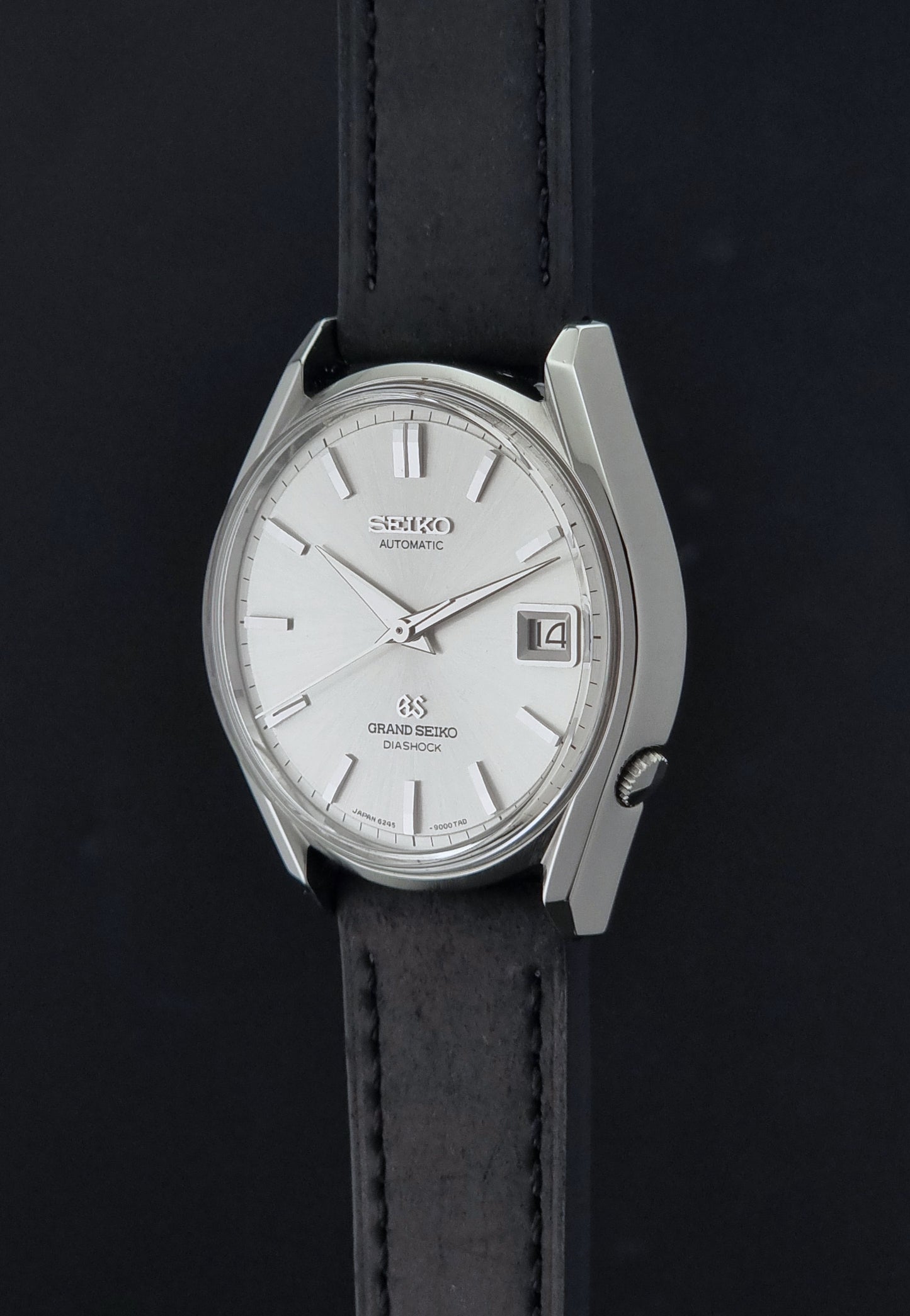 Vintage Grand Seiko 6245-9001 Wristwatch with a black leather strap on a dark background crown profile view