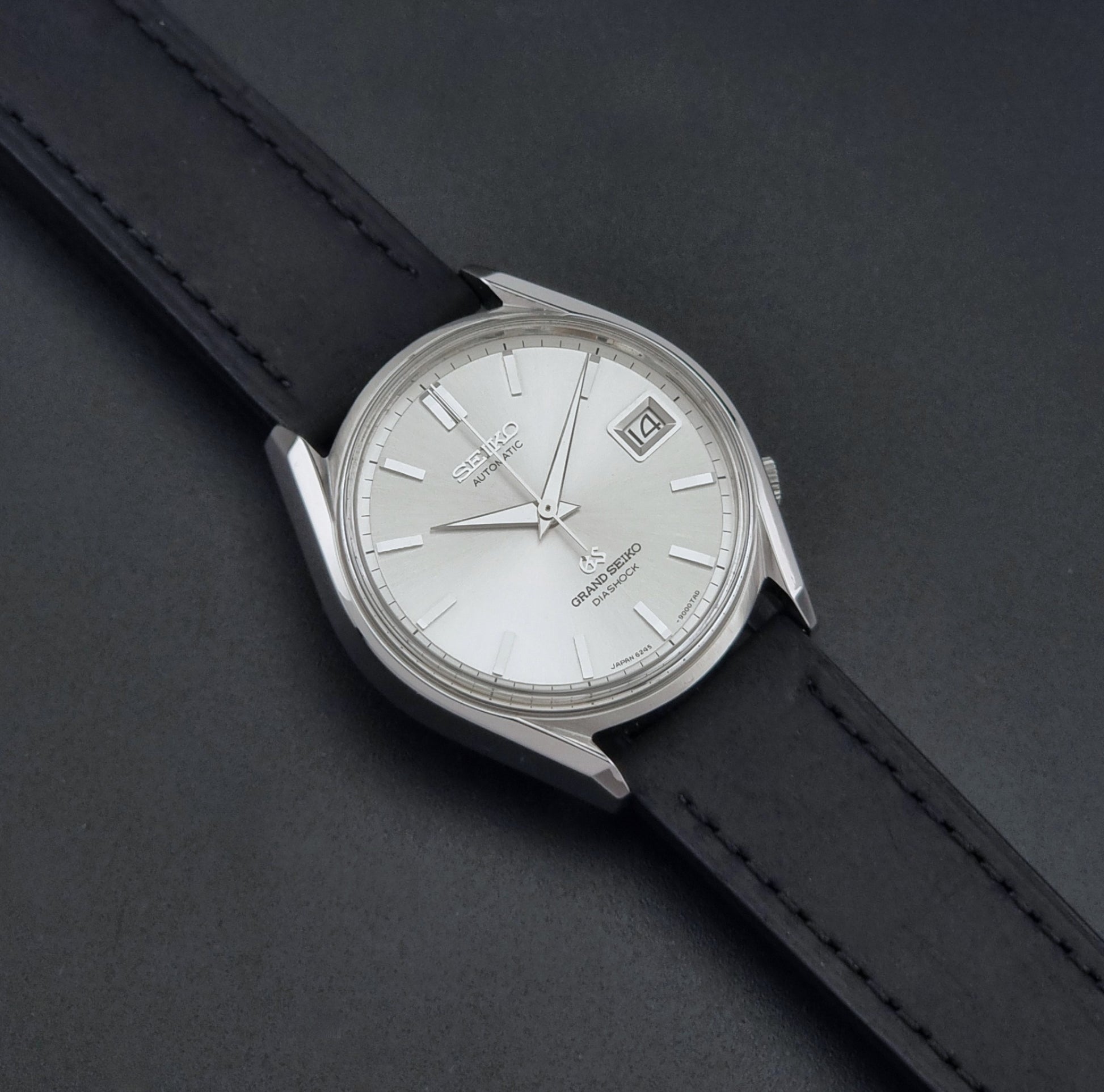 Vintage Grand Seiko 6245-9001 Wristwatch with a black leather strap on a dark background dial
