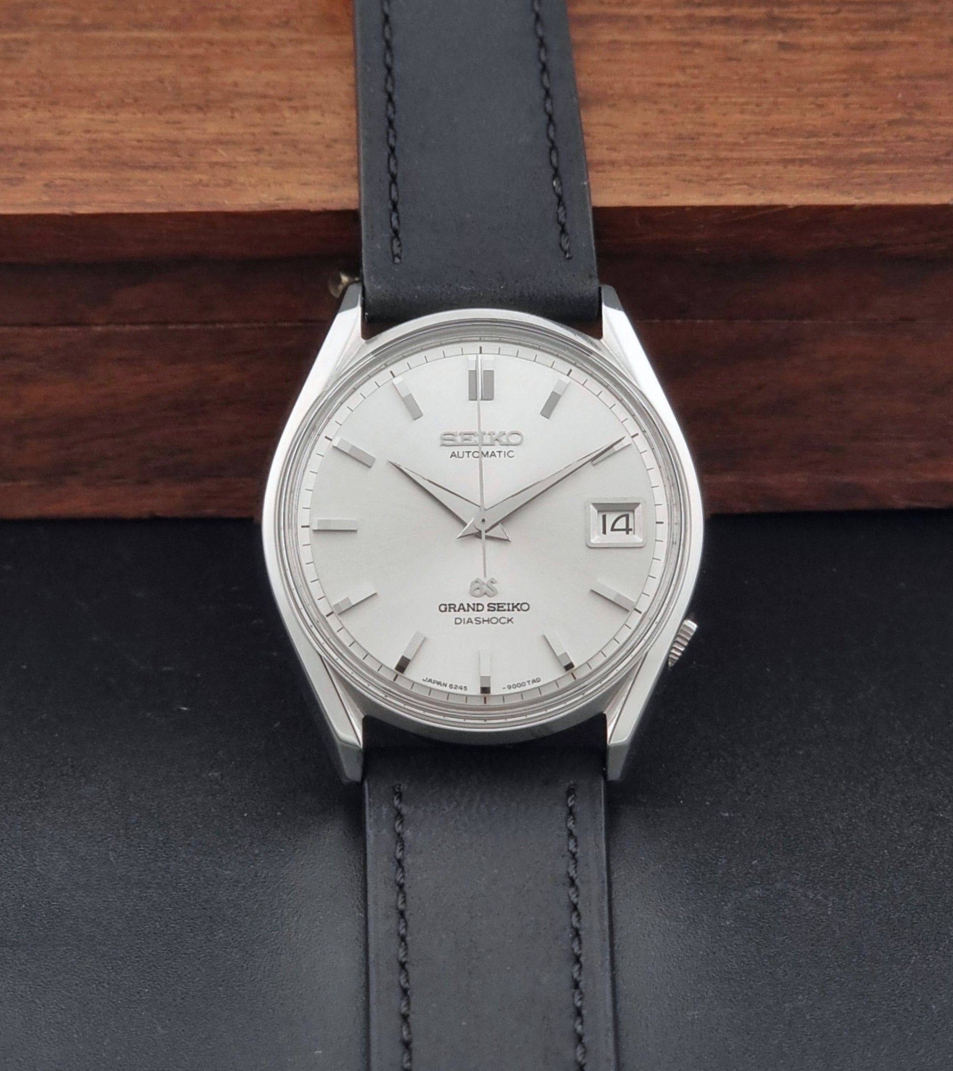 Vintage Grand Seiko 6245-9001 Wristwatch with a black leather strap on a dark background dial view