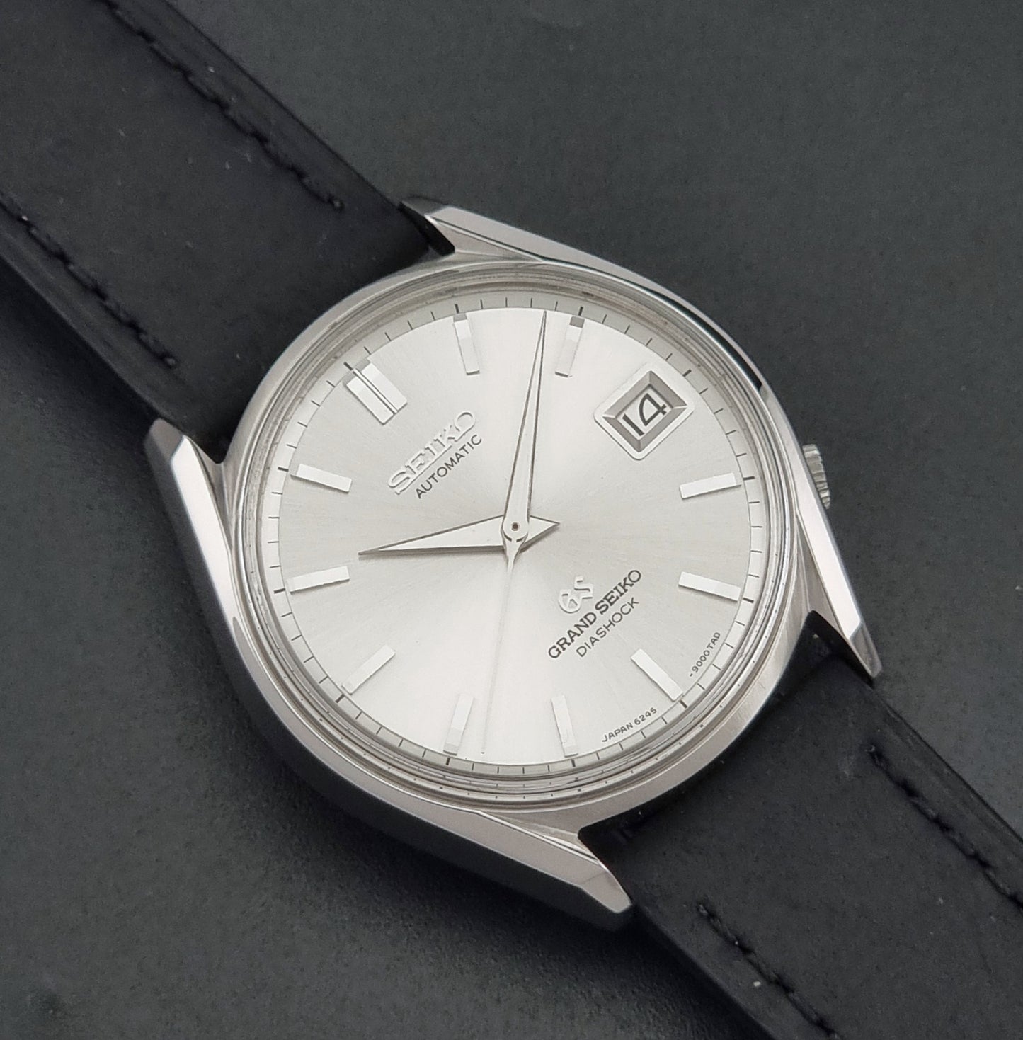 Vintage Grand Seiko 6245-9001 Wristwatch with a black leather strap on a dark background close up dial view