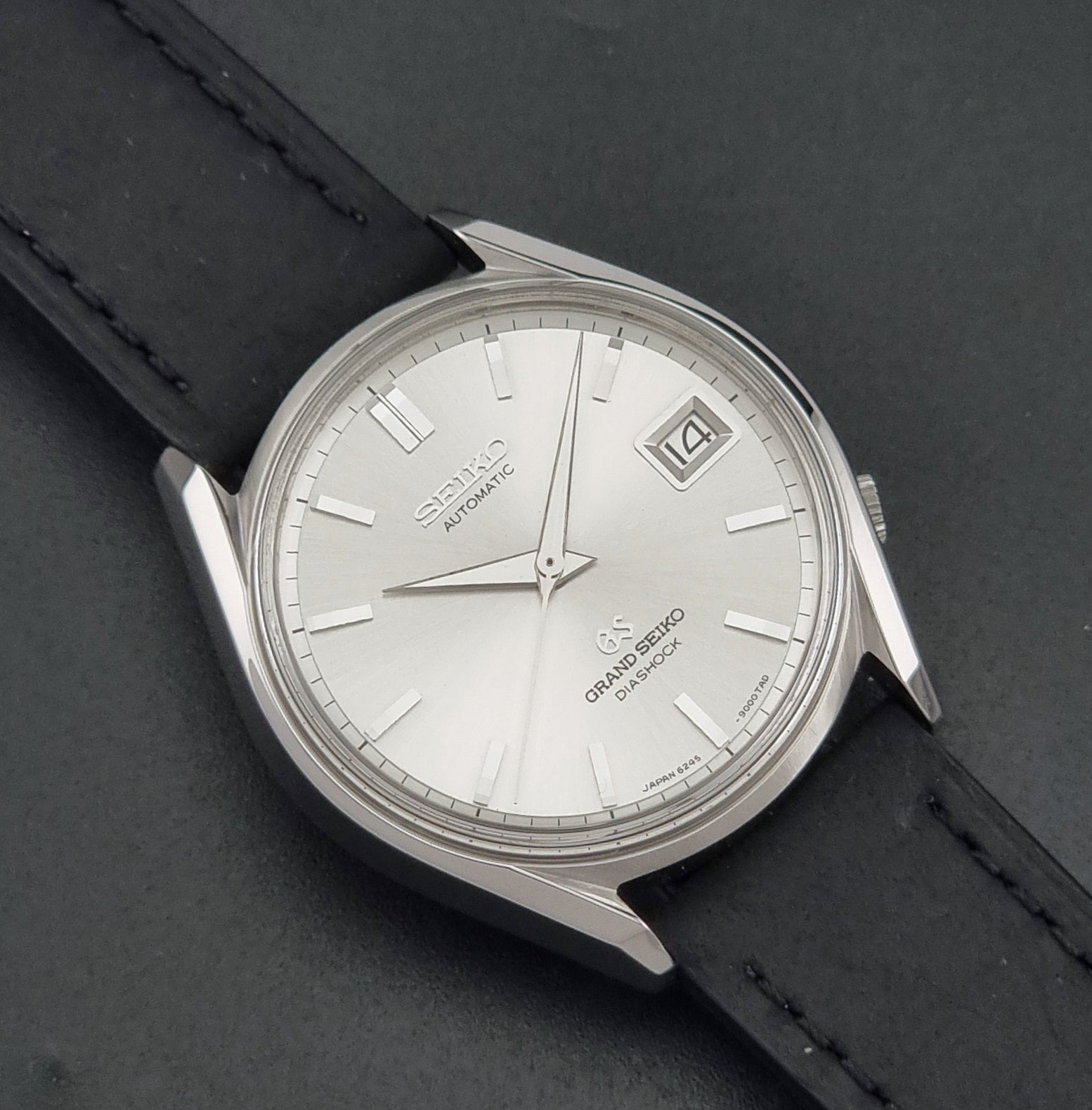 Vintage Grand Seiko 6245-9001 Wristwatch with a black leather strap on a dark background close up dial view