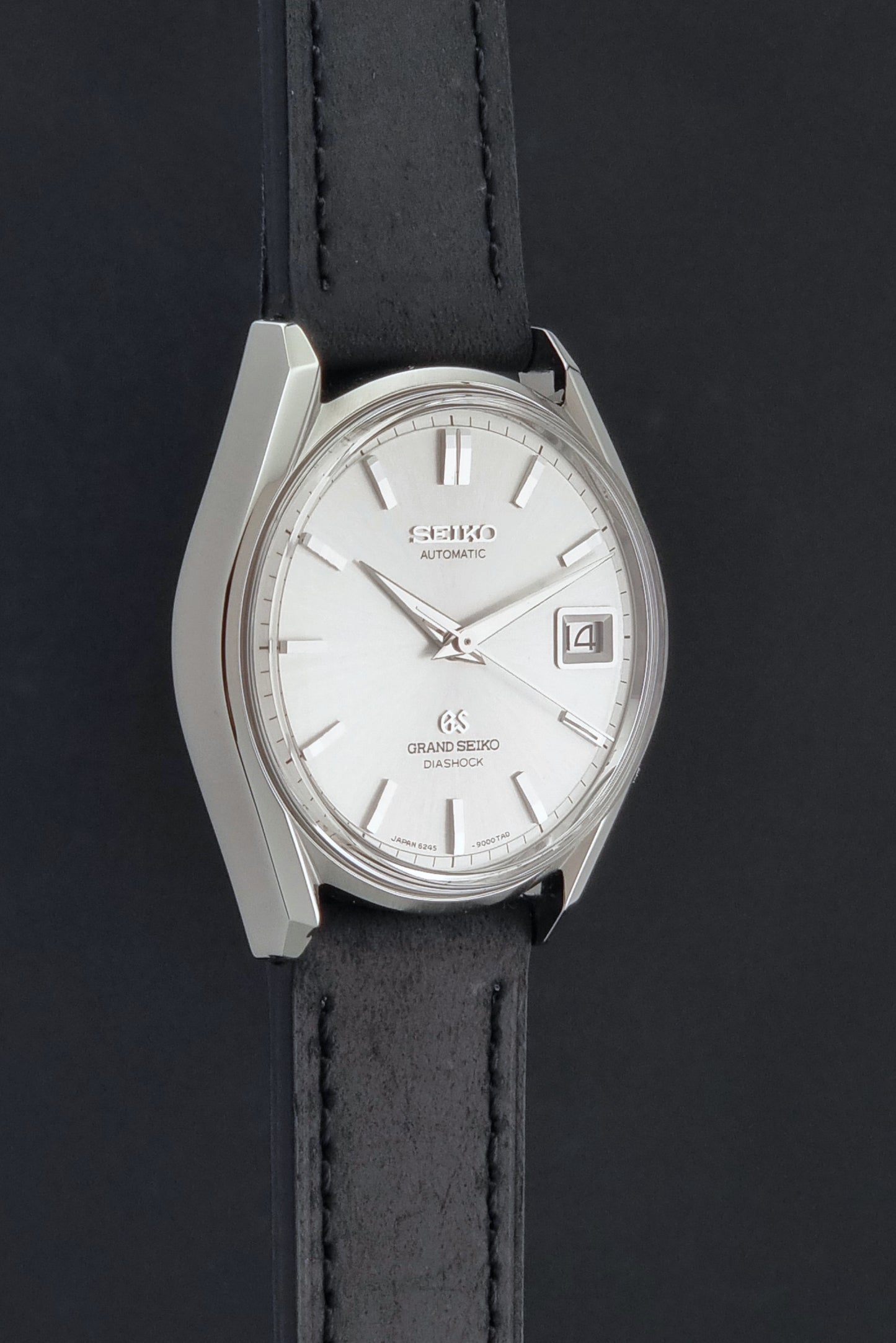 Vintage Grand Seiko 6245-9001 Wristwatch with a black leather strap on a dark background side profile view