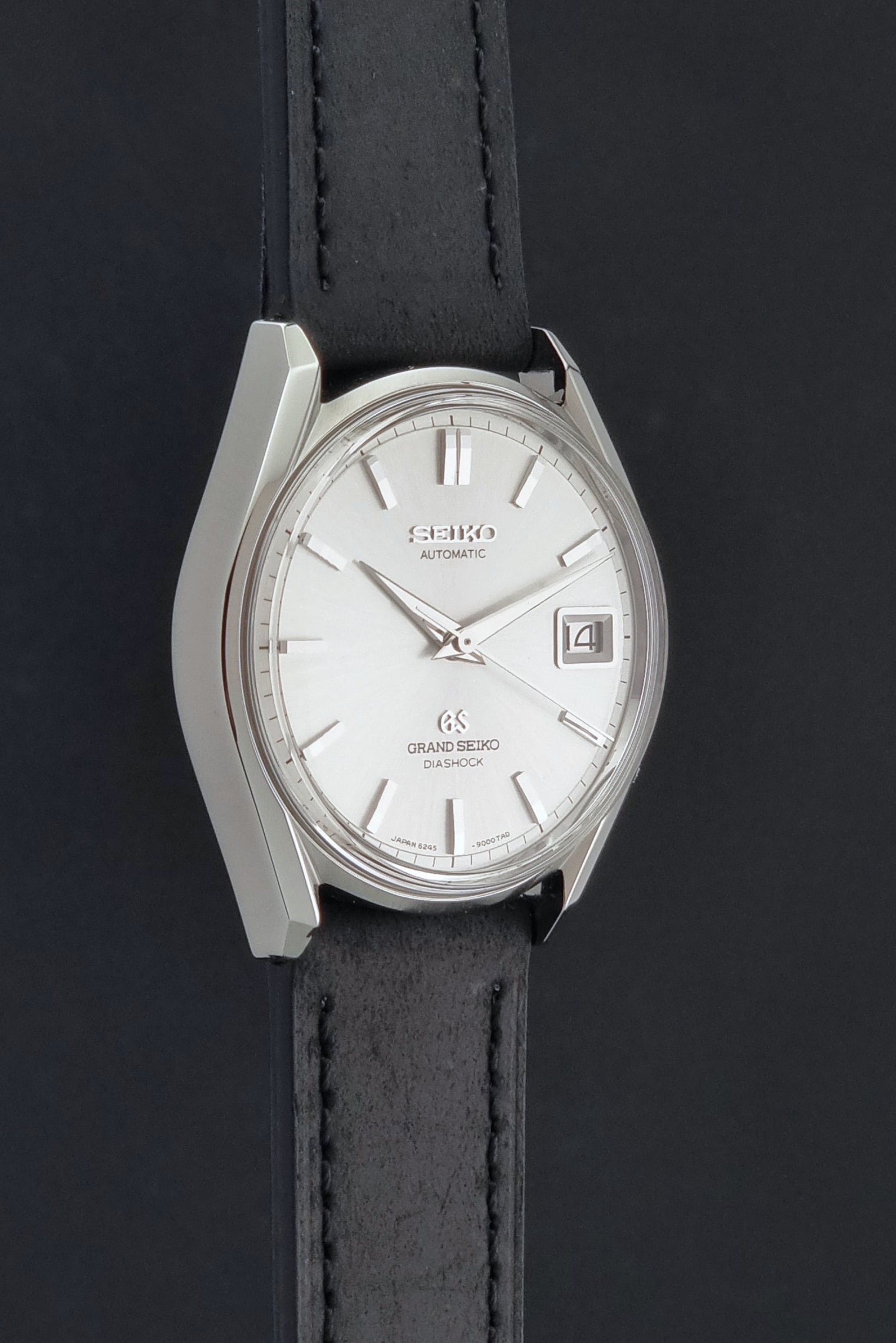 Vintage Grand Seiko 6245-9001 Wristwatch with a black leather strap on a dark background side profile view