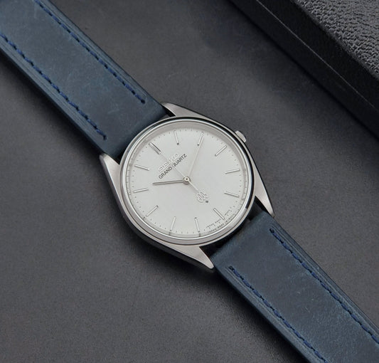 Vintage Seiko Grand Quartz Wristwatch 9940-8000 Twin Quartz with blue strap and silver case on a dark gray background dial