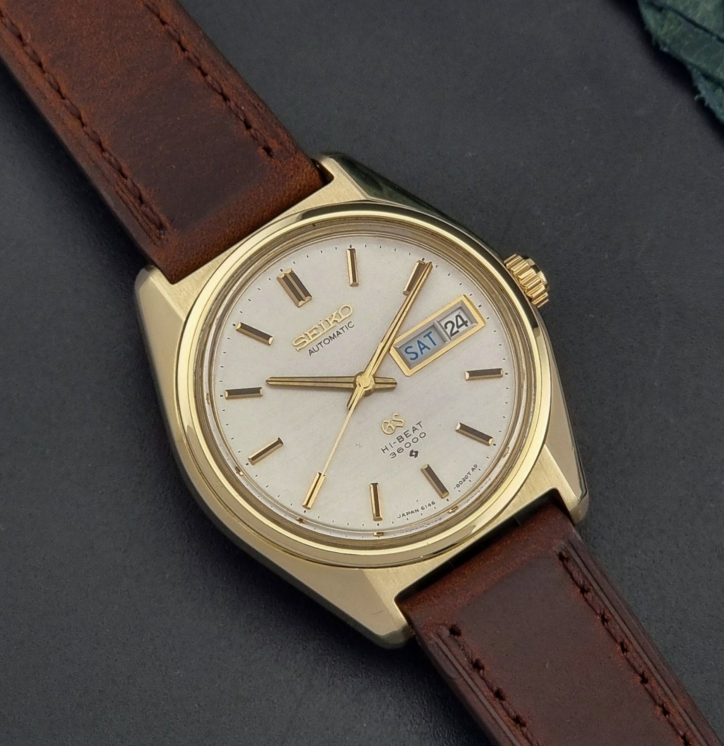 Vintage  Grand Seiko watch 6146-8000 watch with gold case and brown leather strap on a dark background close up dial view
