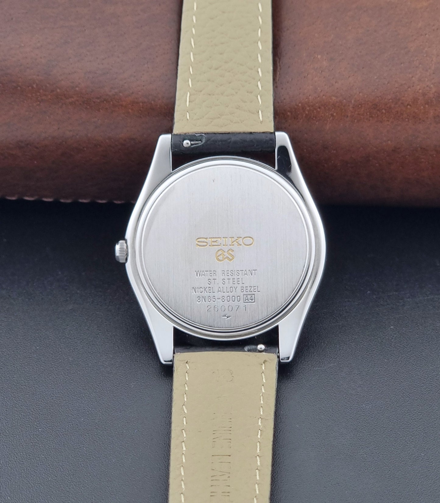 Vintage Grand Seiko SBGG003 watch  8N65-8000 with black leather strap on a dark surface case back view