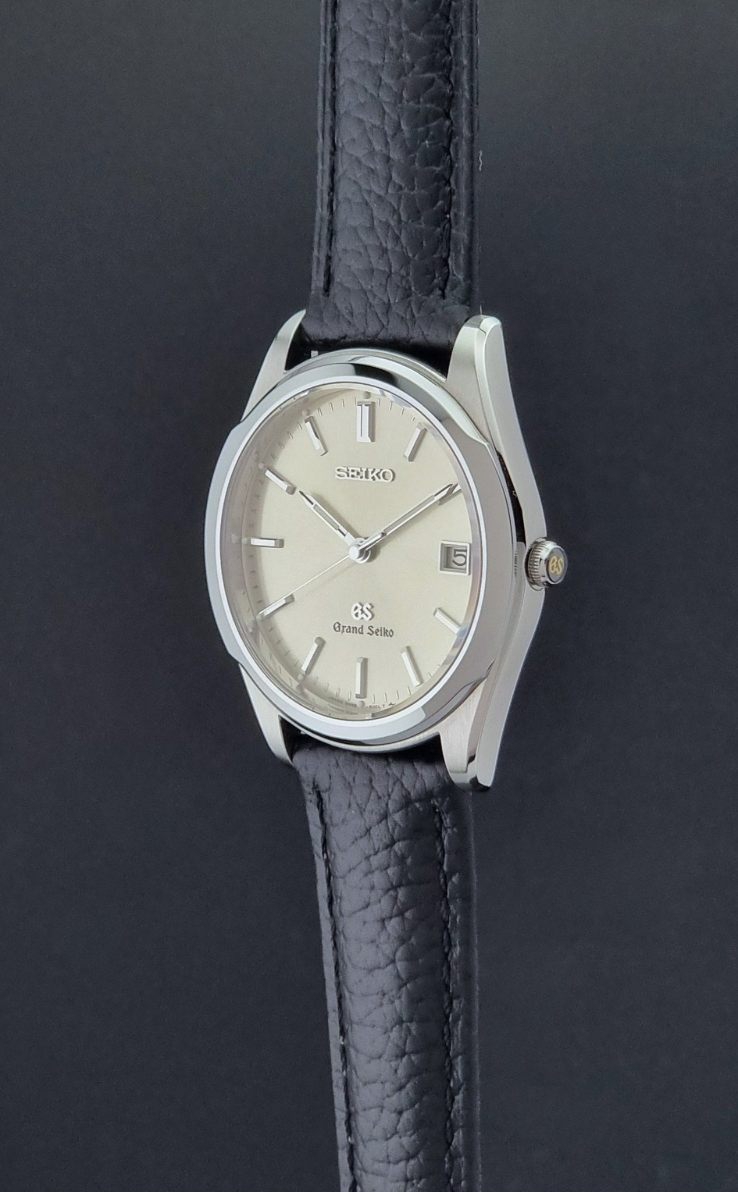 Vintage Grand Seiko SBGG003 watch  8N65-8000 with black leather strap on a dark surface crown profile view