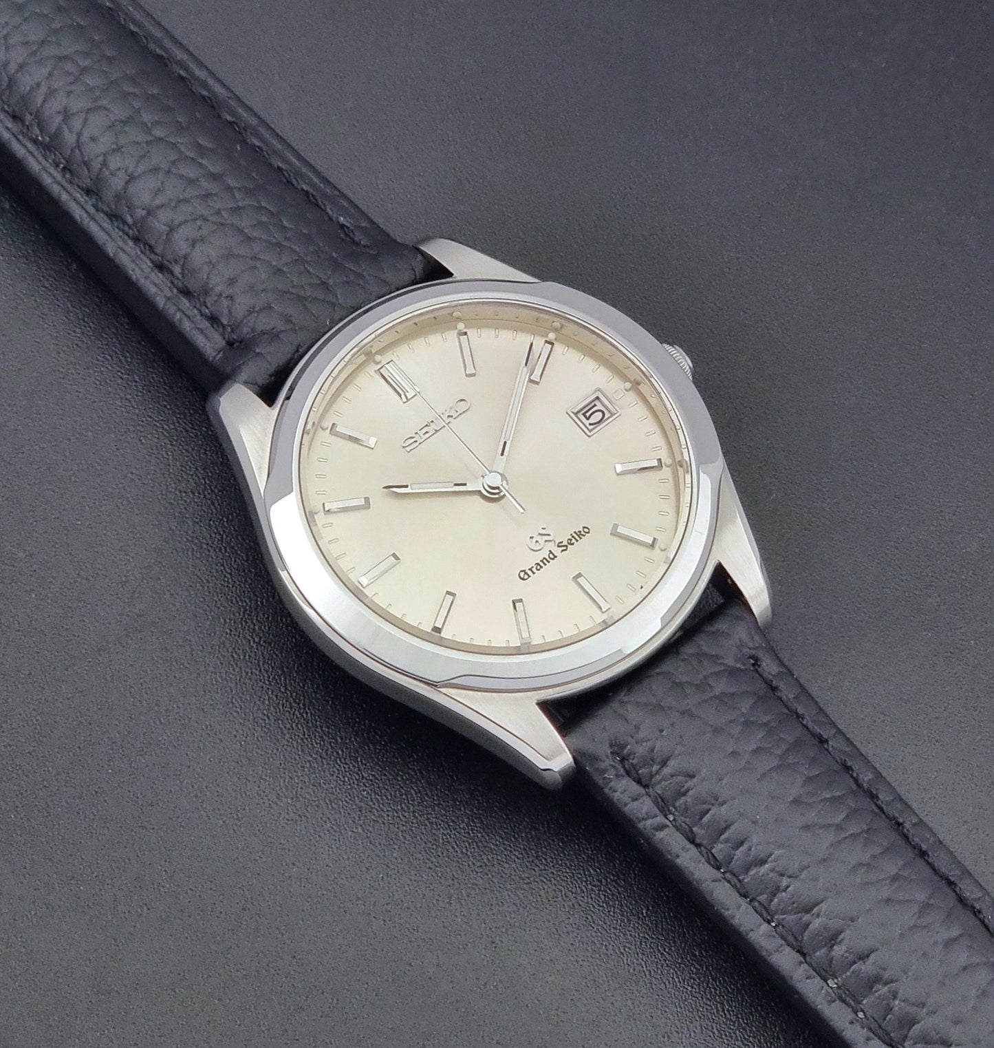 Vintage Grand Seiko SBGG003 watch  8N65-8000 with black leather strap on a dark surface front view