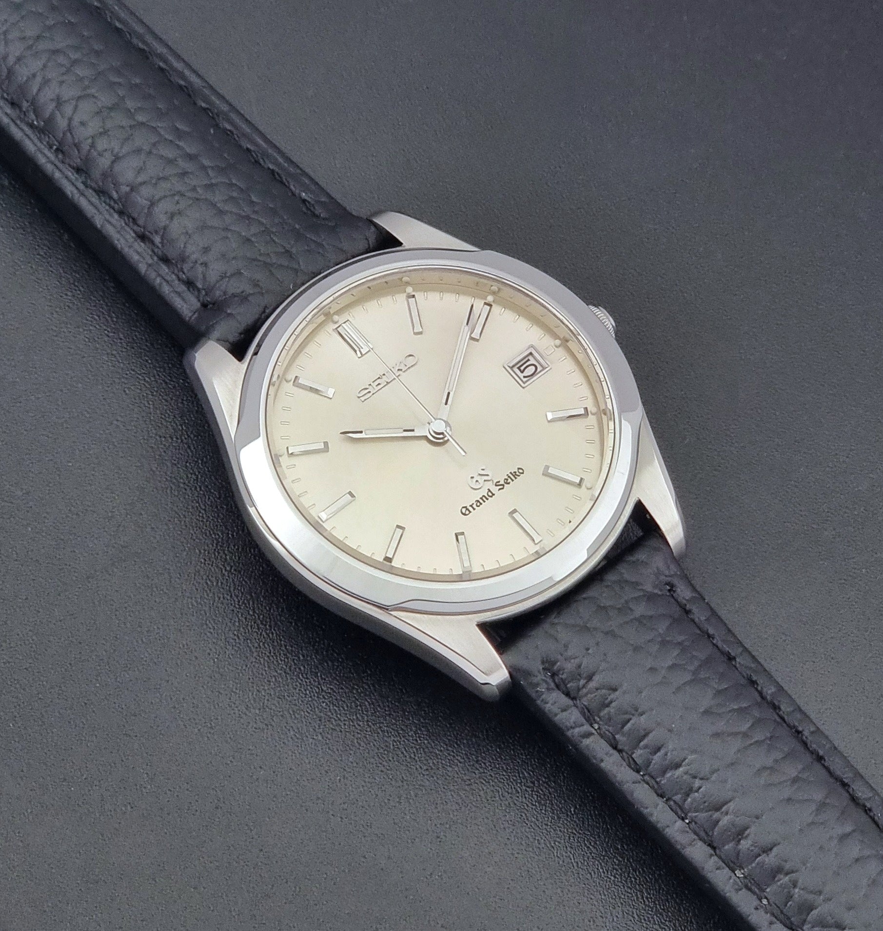 Vintage Grand Seiko SBGG003 watch  8N65-8000 with black leather strap on a dark surface front view