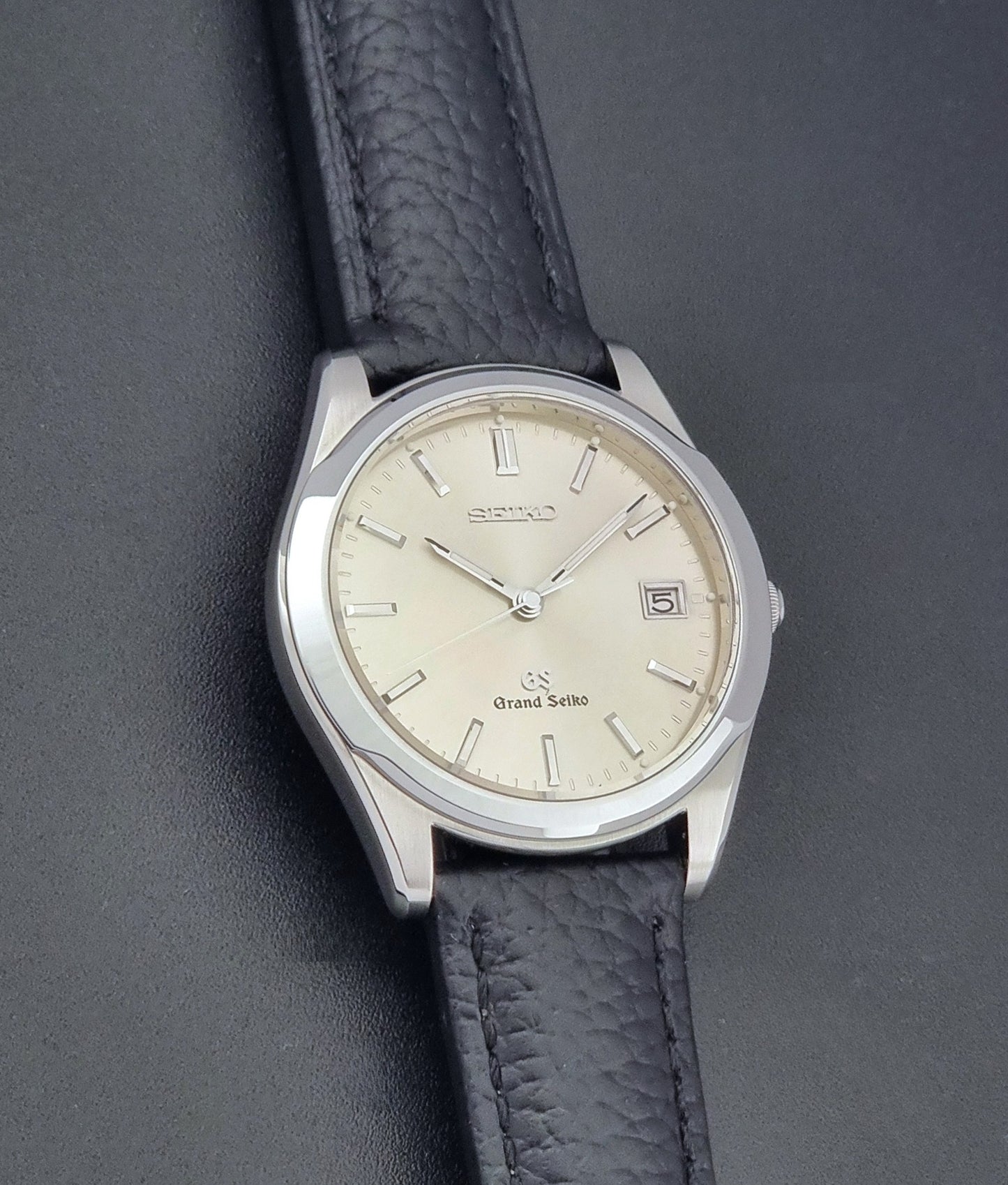 Vintage Grand Seiko SBGG003 watch  8N65-8000 with black leather strap on a dark surface close up dial view