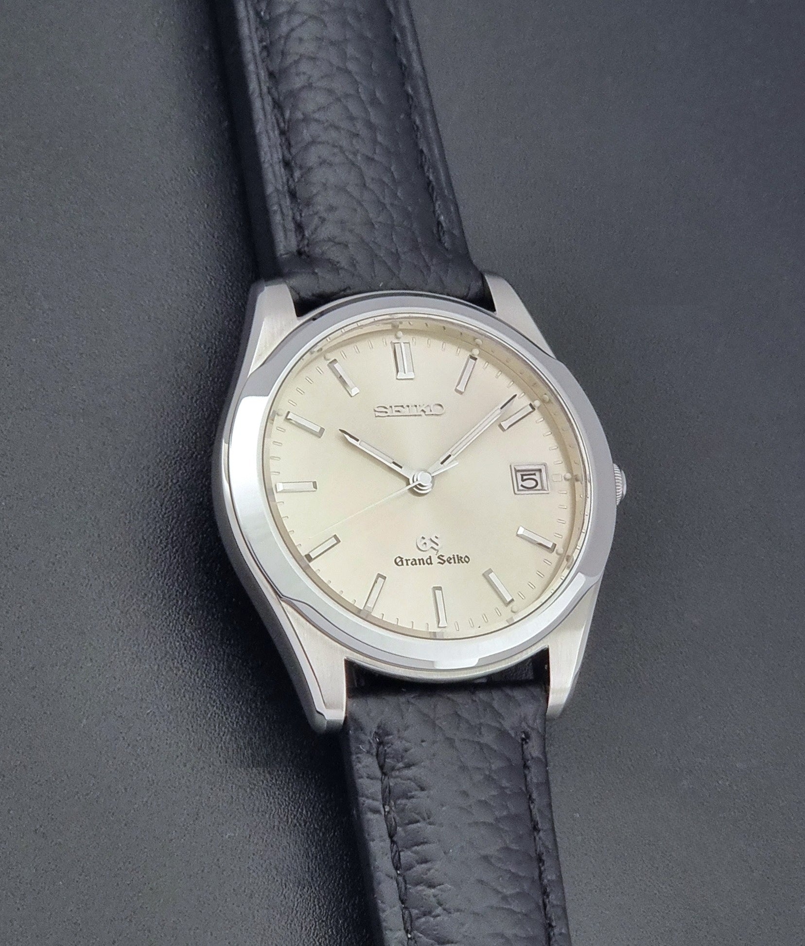 Vintage Grand Seiko SBGG003 watch  8N65-8000 with black leather strap on a dark surface close up dial view