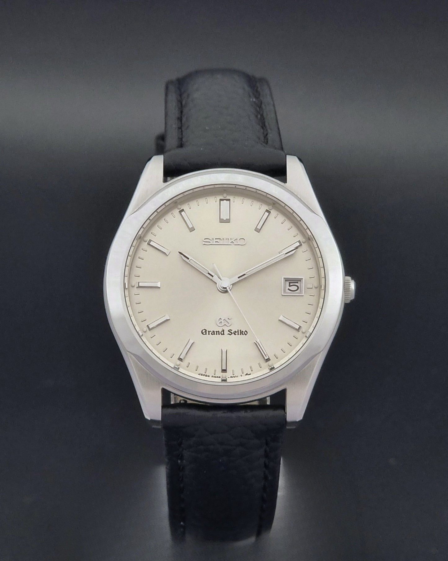 Vintage Grand Seiko SBGG003 watch  8N65-8000 with black leather strap on a dark surface close dial view