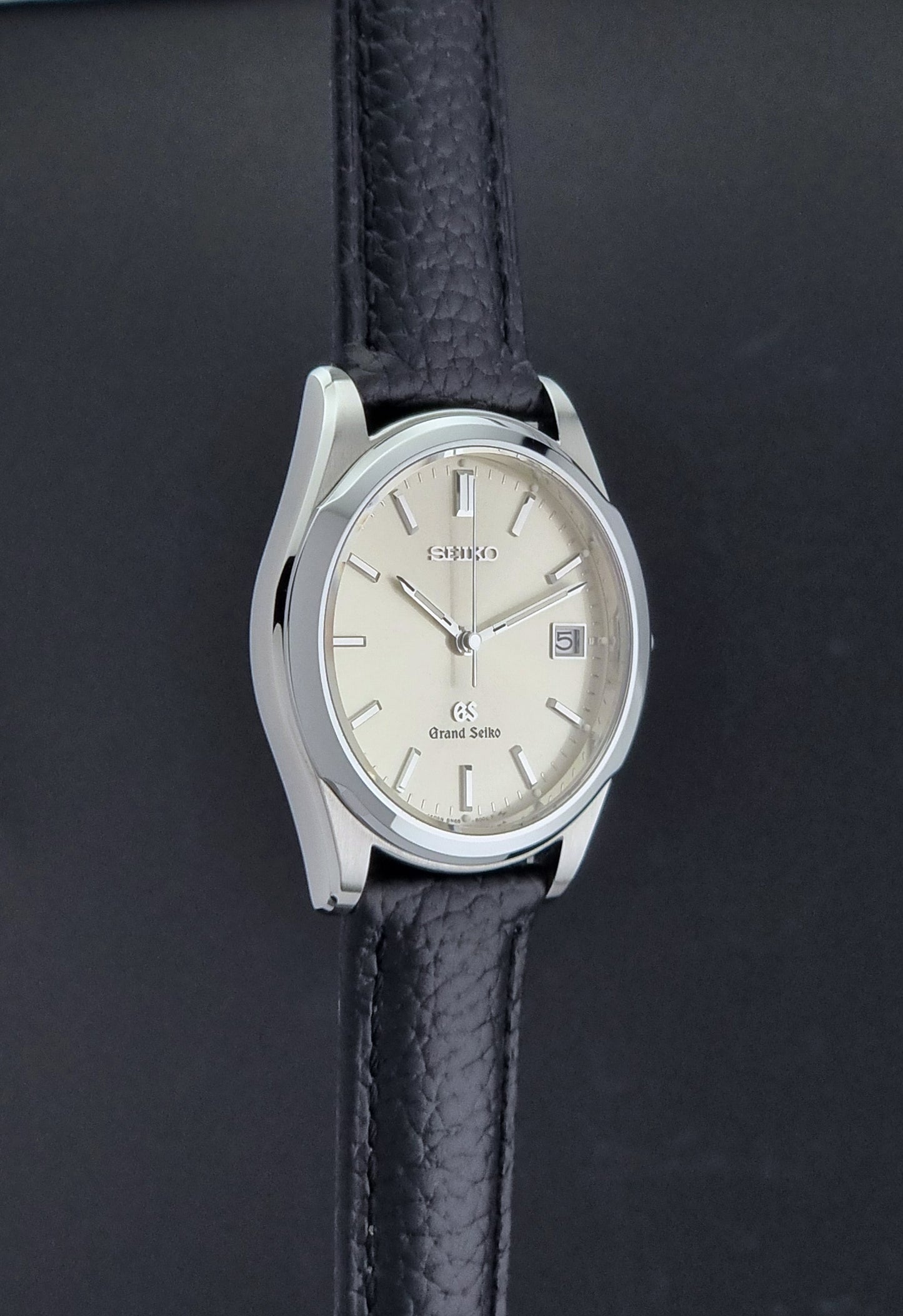 Vintage Grand Seiko SBGG003 watch  8N65-8000 with black leather strap on a dark surface side profile view