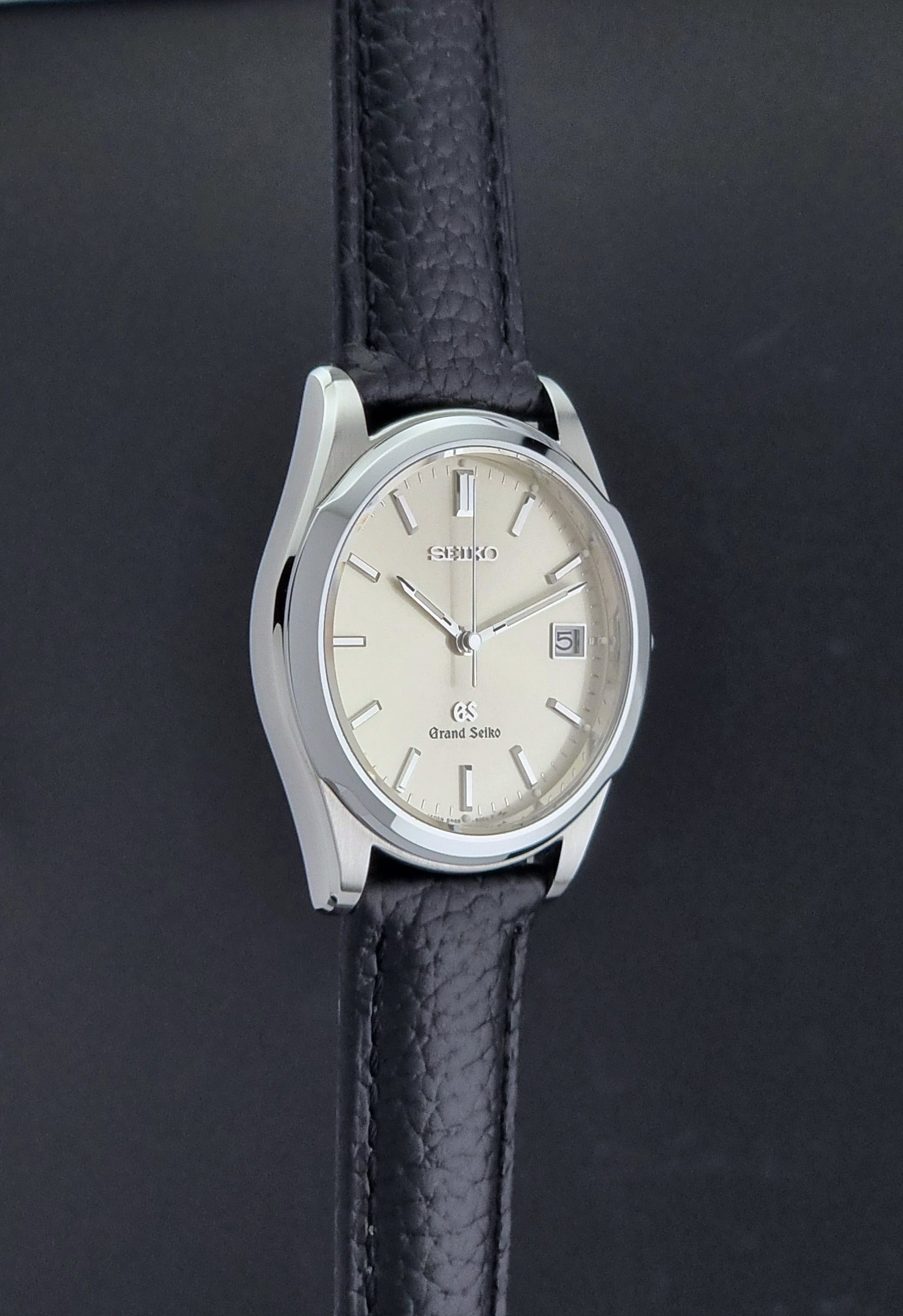 Vintage Grand Seiko SBGG003 watch  8N65-8000 with black leather strap on a dark surface side profile view