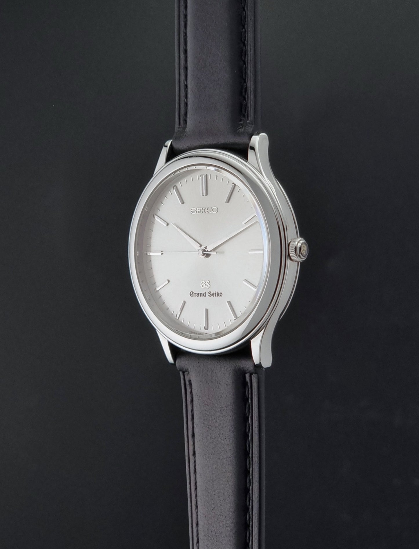 Vintage Grand Seiko 9581-7000 Quartz with black strap and silver case on a brown background crown profile view