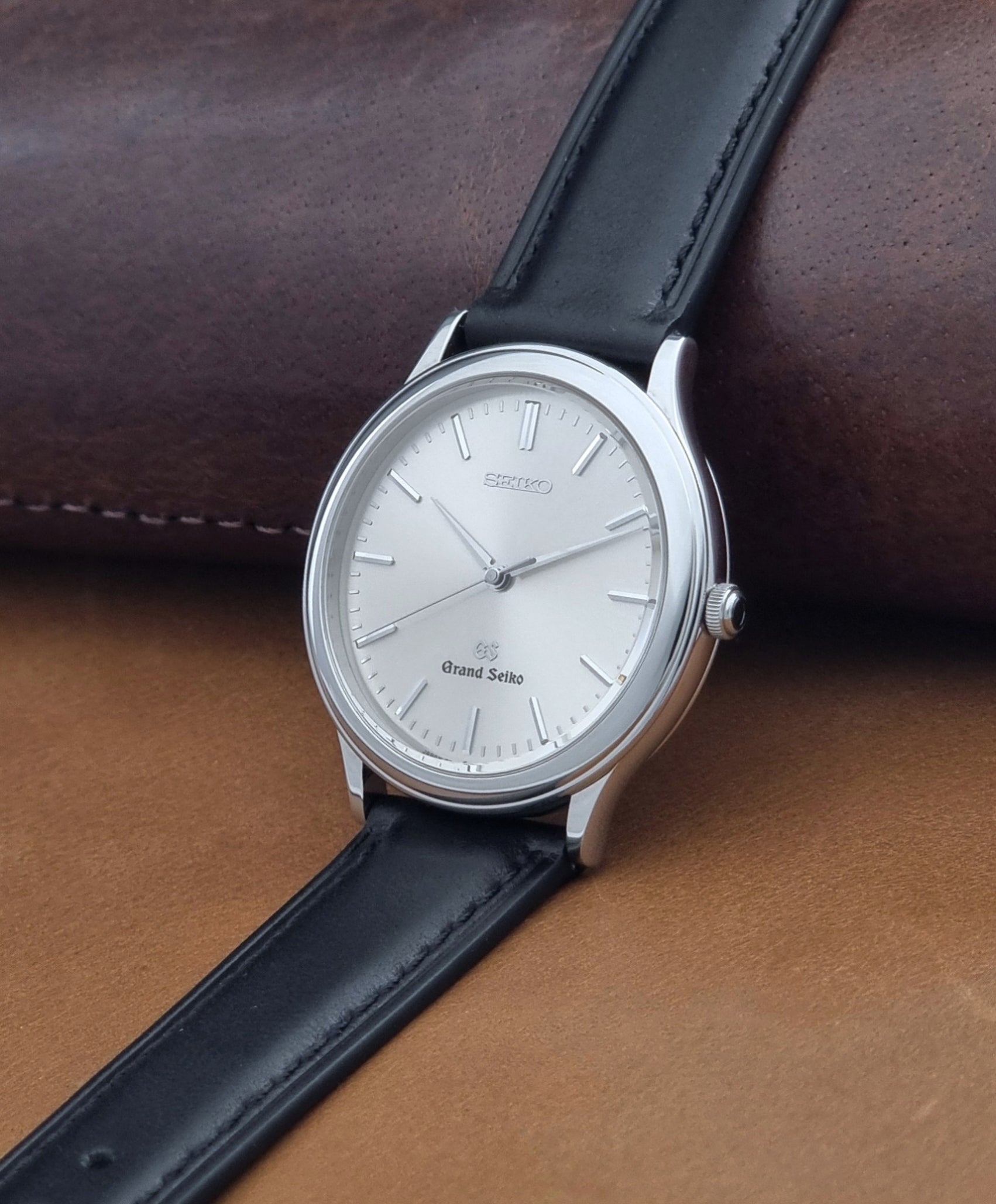 Vintage Grand Seiko 9581-7000 Quartz with black strap and silver case on a brown background crown view