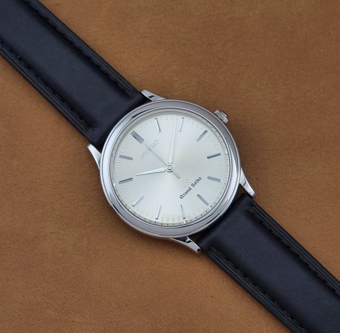 Vintage Grand Seiko 9581-7000 Quartz with black strap and silver case on a brown background dial