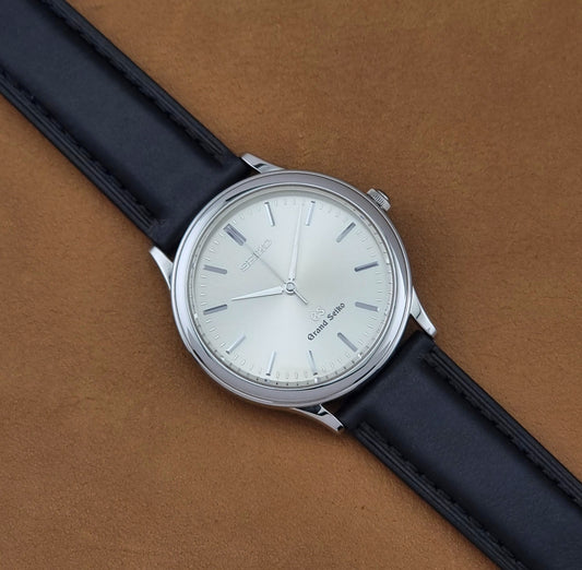 Vintage Grand Seiko 9581-7000 Quartz with black strap and silver case on a brown background dial