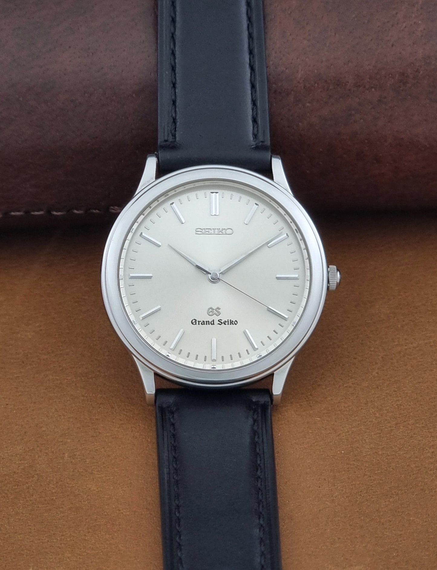 Vintage Grand Seiko 9581-7000 Quartz with black strap and silver case on a brown background dial view