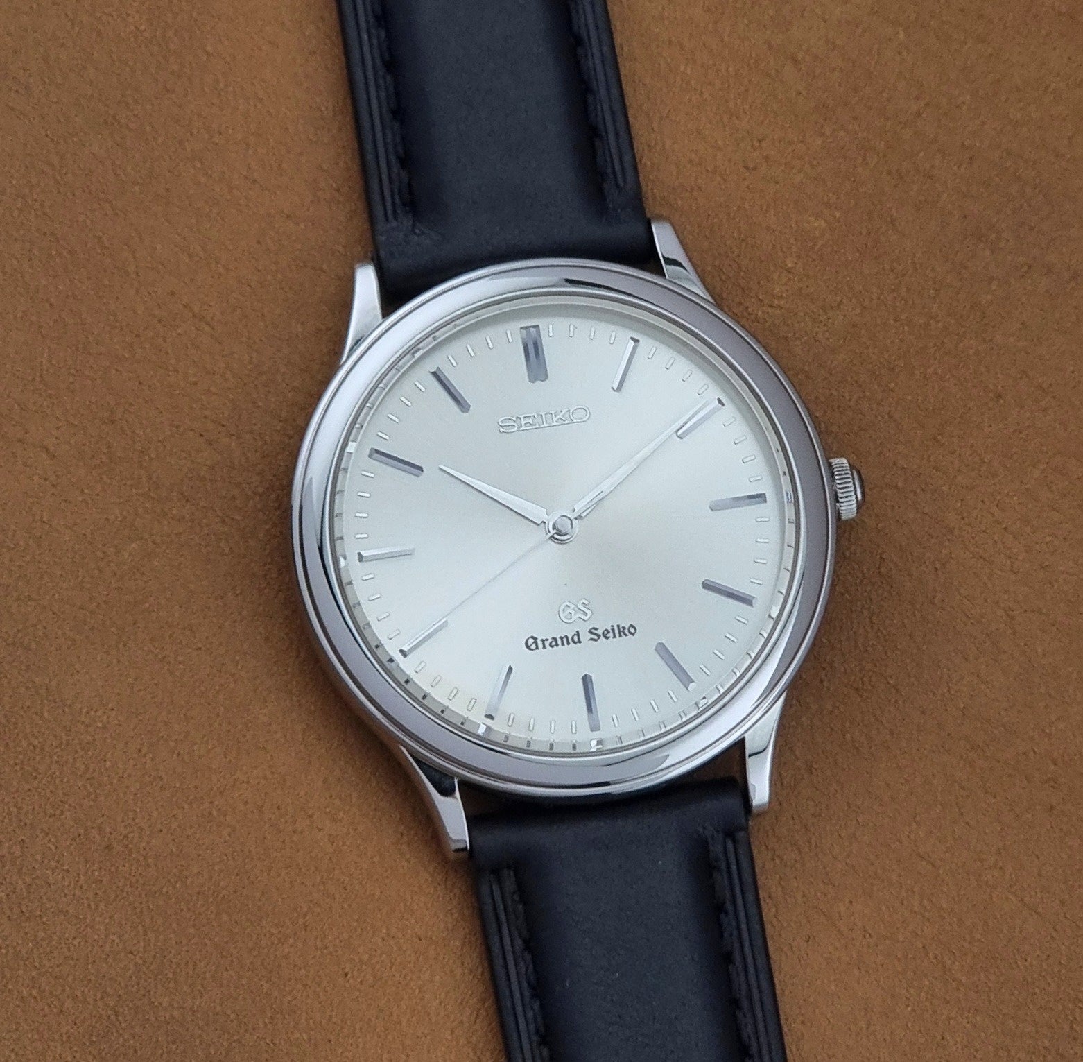 Vintage Grand Seiko 9581-7000 Quartz with black strap and silver case on a brown background front view
