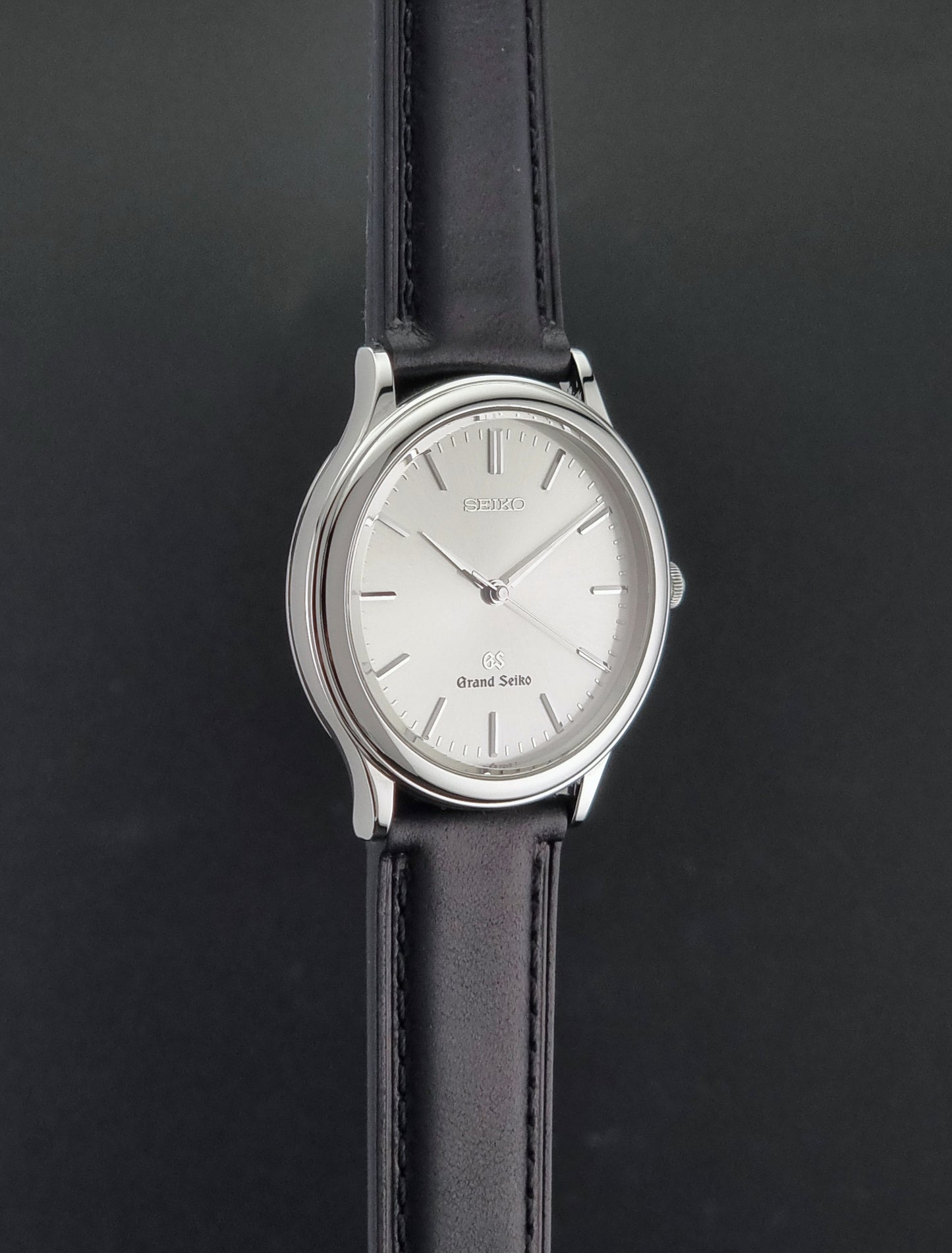 Vintage Grand Seiko 9581-7000 Quartz with black strap and silver case on a brown background side profile view