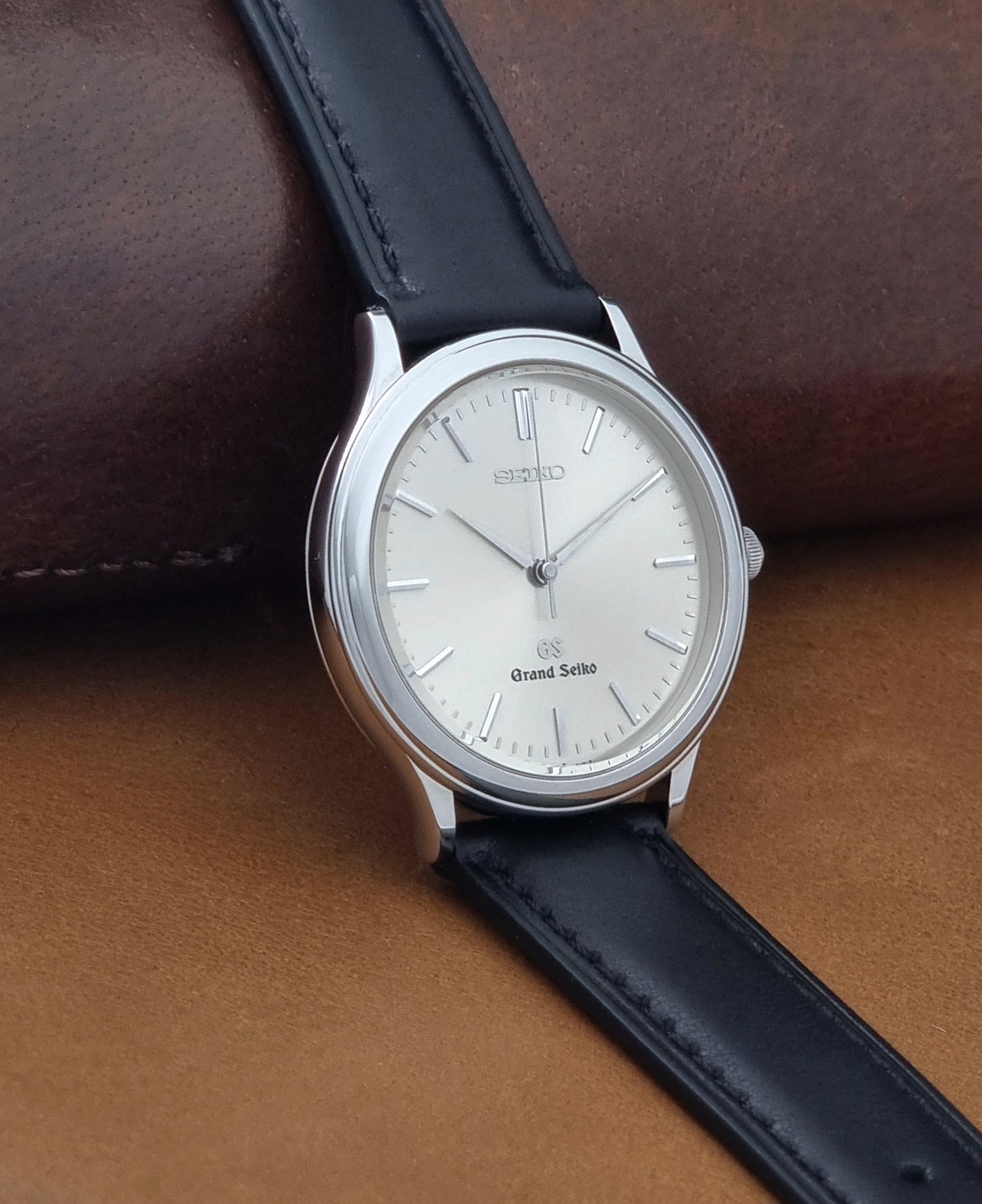 Vintage Grand Seiko 9581-7000 Quartz with black strap and silver case on a brown background side view