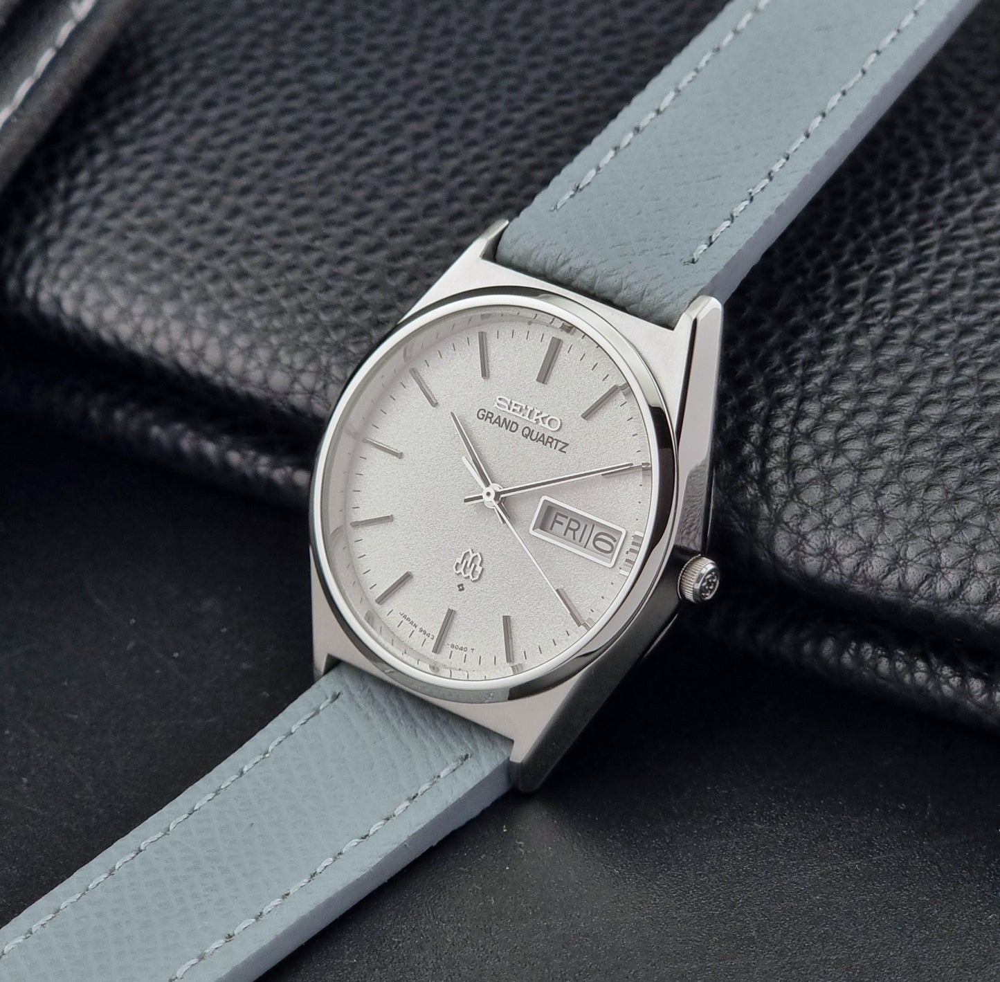 Vintage Seiko Grand Quartz watch 9943-8030 with a leather strap on a dark gray background crown view